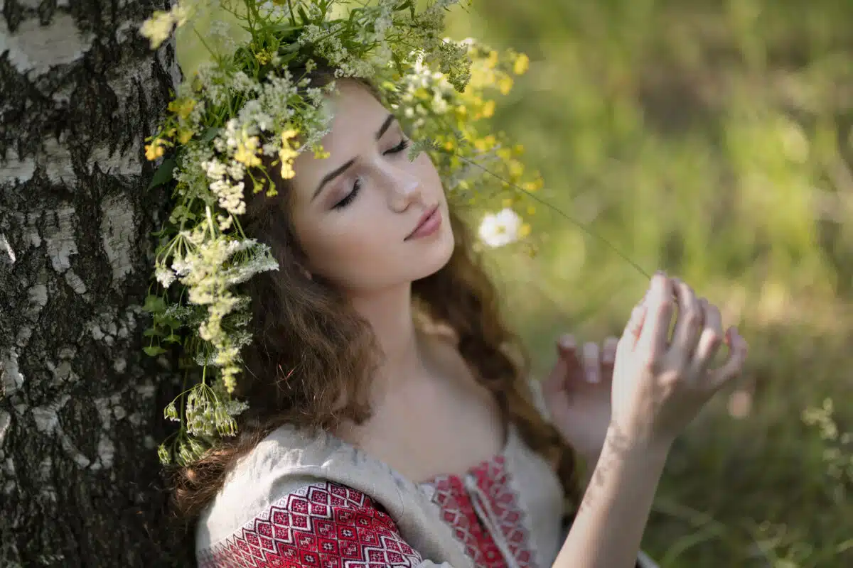 Close-up portrait of a girl in a wreath of flowers near a birch