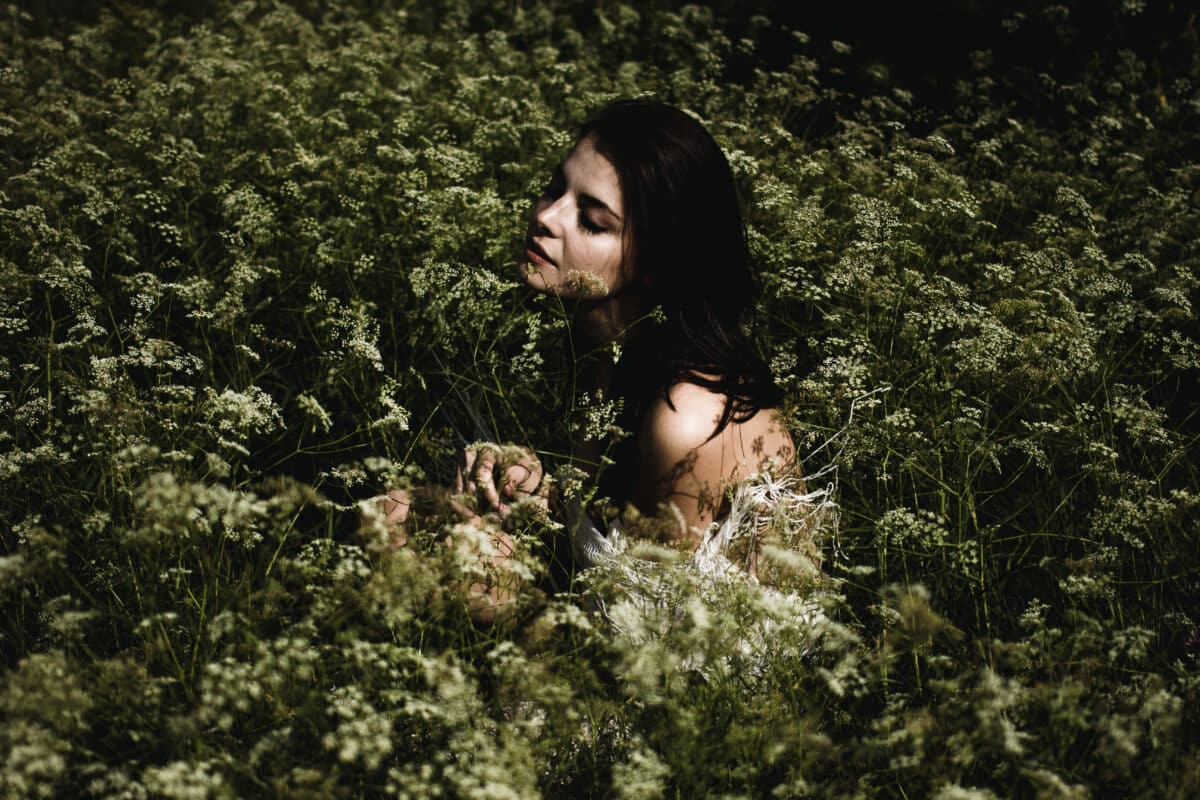 Young woman with black hair and sitting among wildflowers