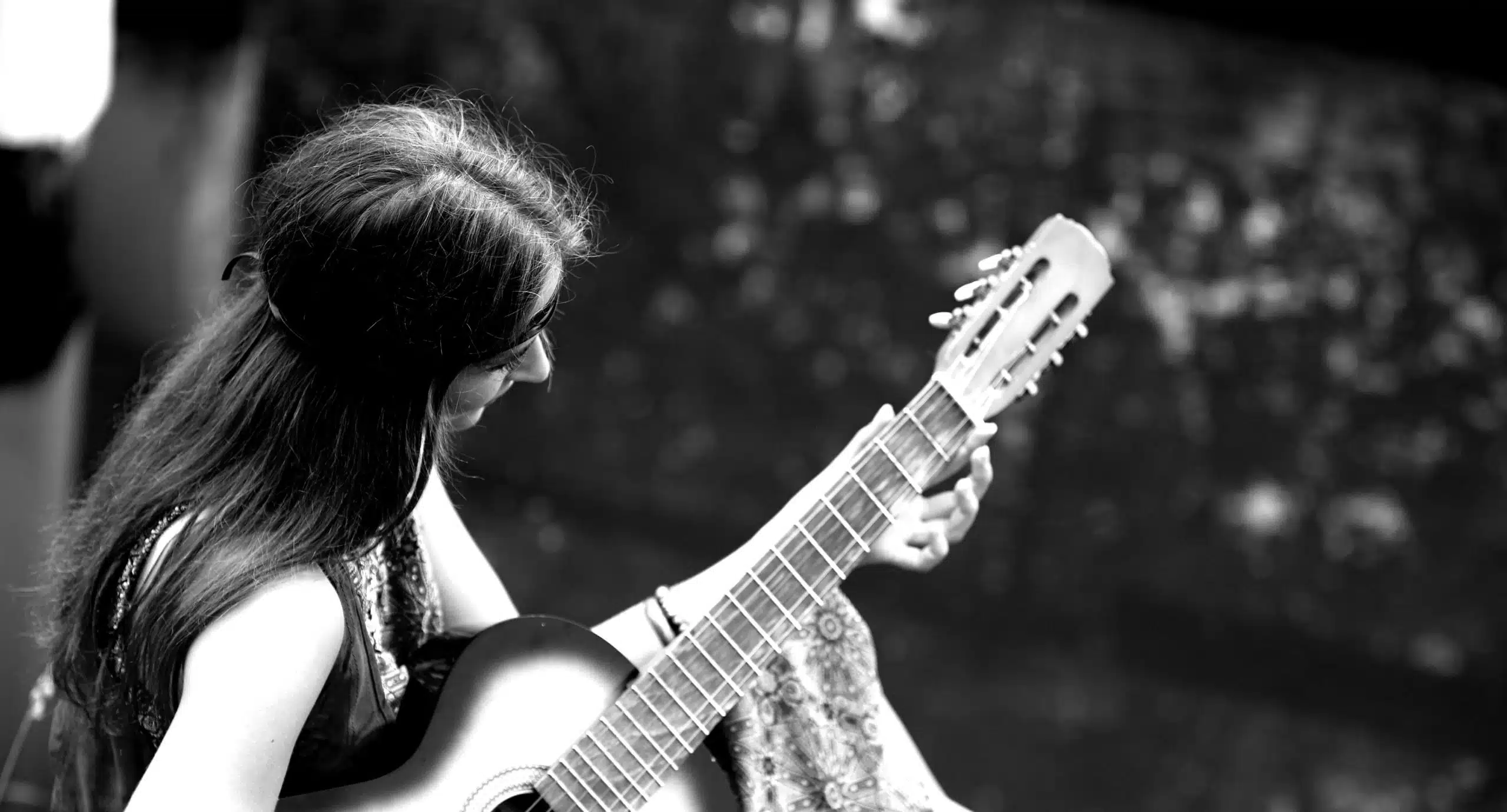 beautiful hippie girl playing guitar near forest lake