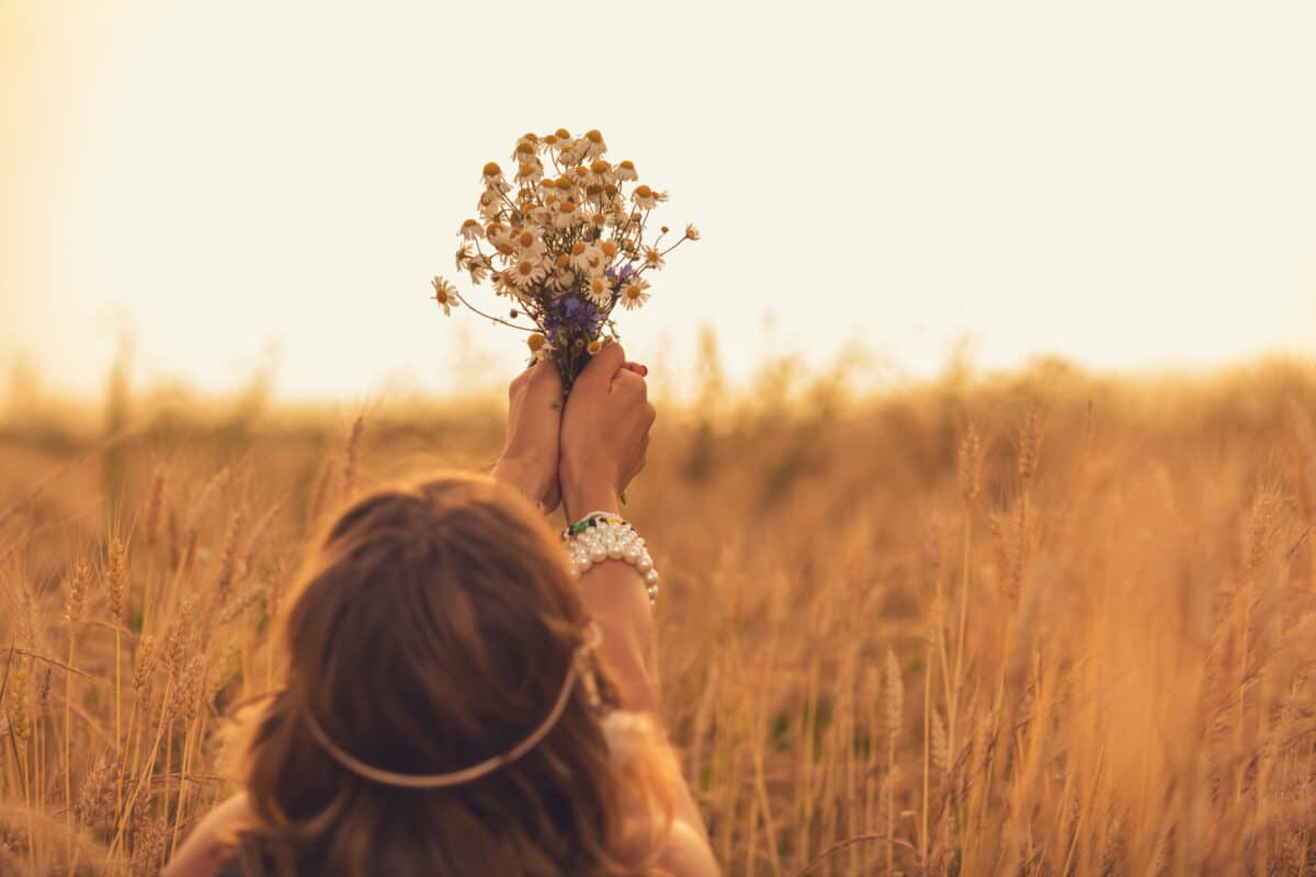 Girl holding a flower bouquet in wheat field.
