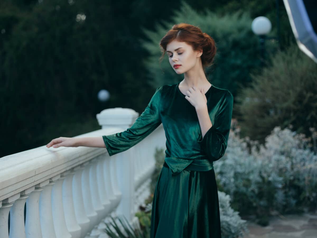 pretty woman leaning on the railing in a green dress park walk