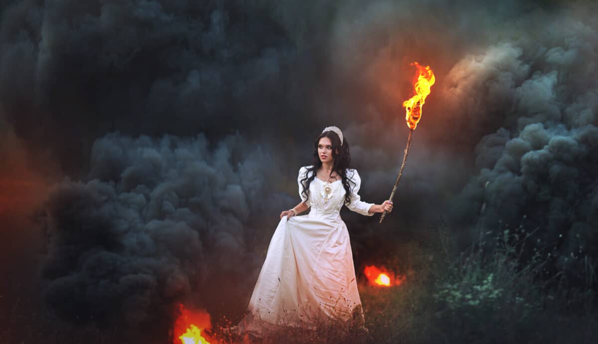 mystical girl with a burning torch out of the woods in fire