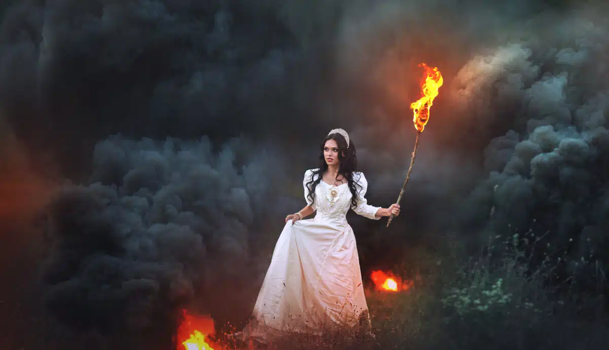 mystical girl with a burning torch out of the woods in fire