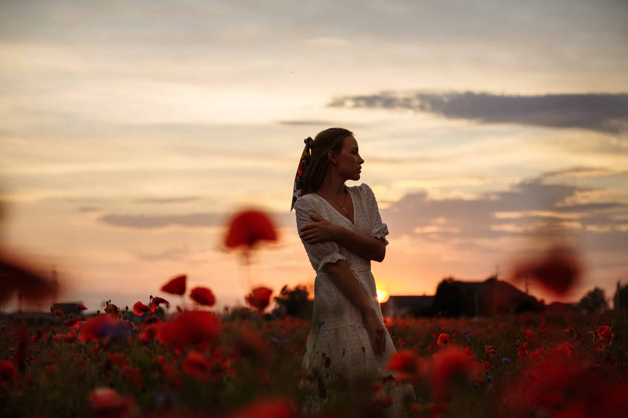 girl in a white dress in a field of poppies at sunset