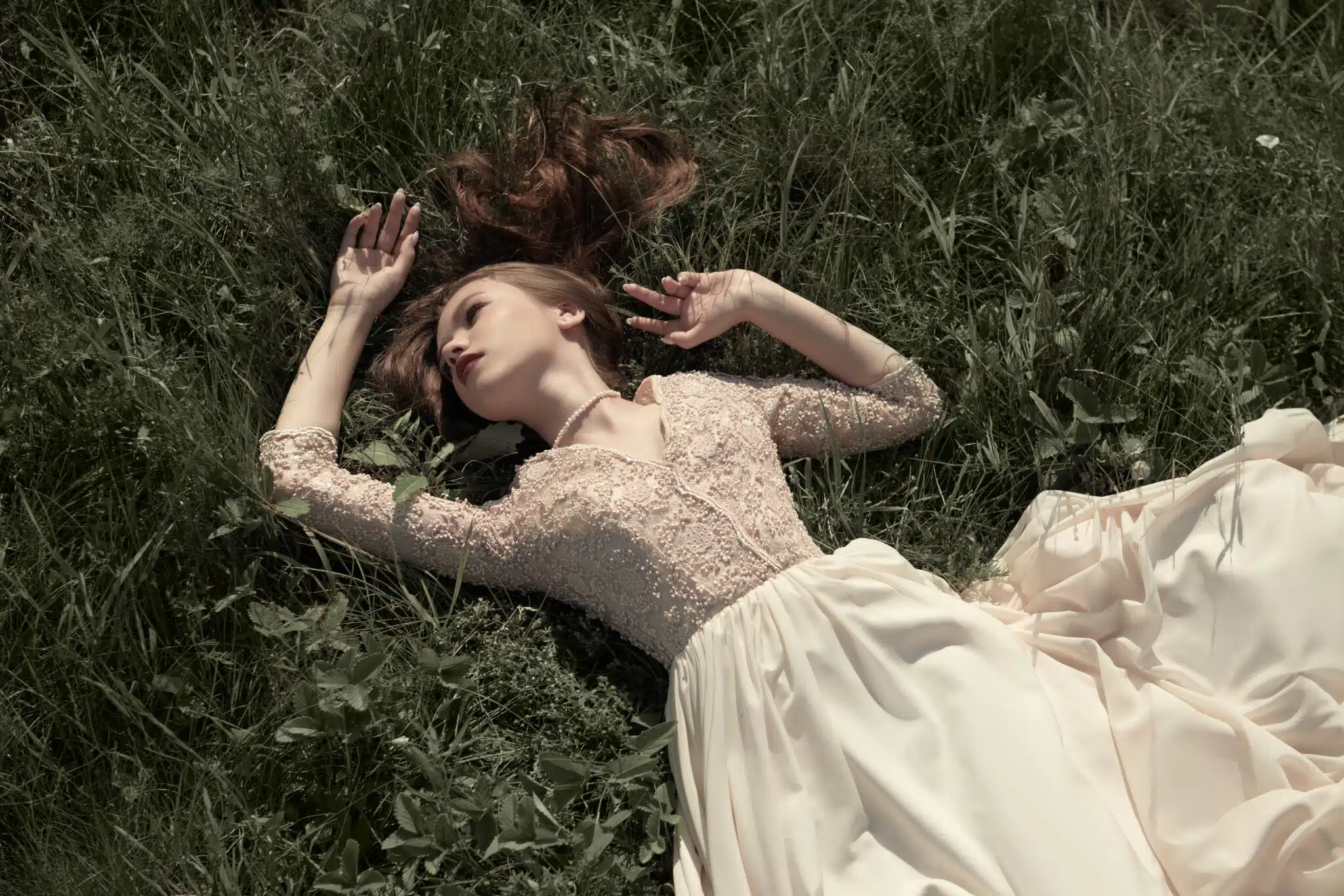 romantic woman in beige dress lying on the grass