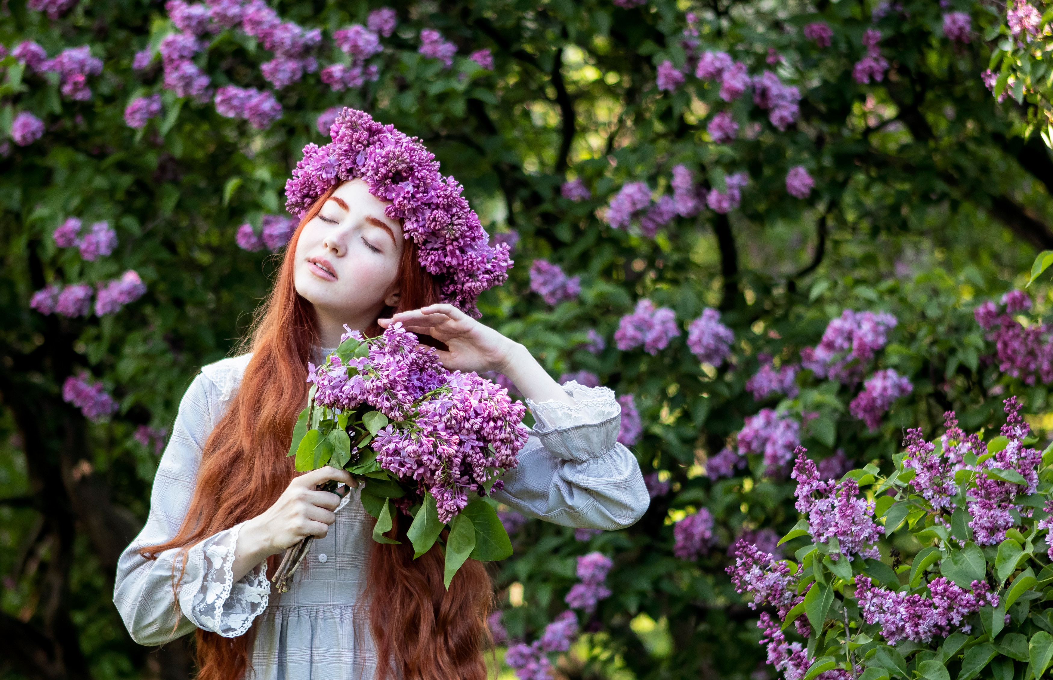 young girl with long red hair with a wreath of lilacs on her head