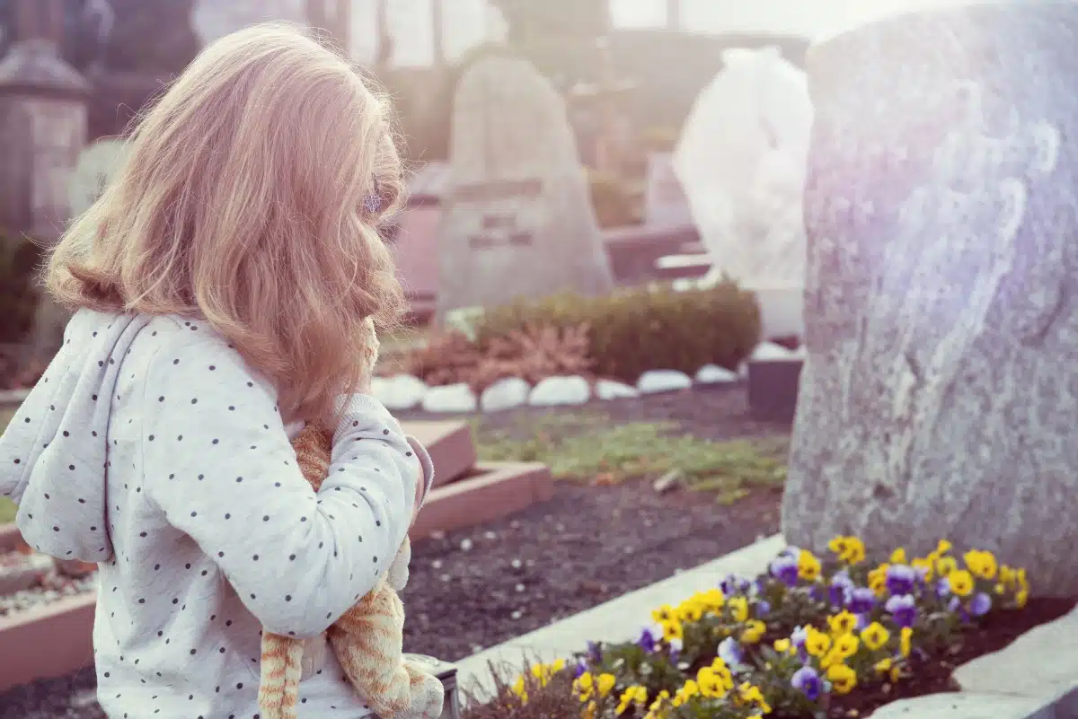 little sad girl in front of grave