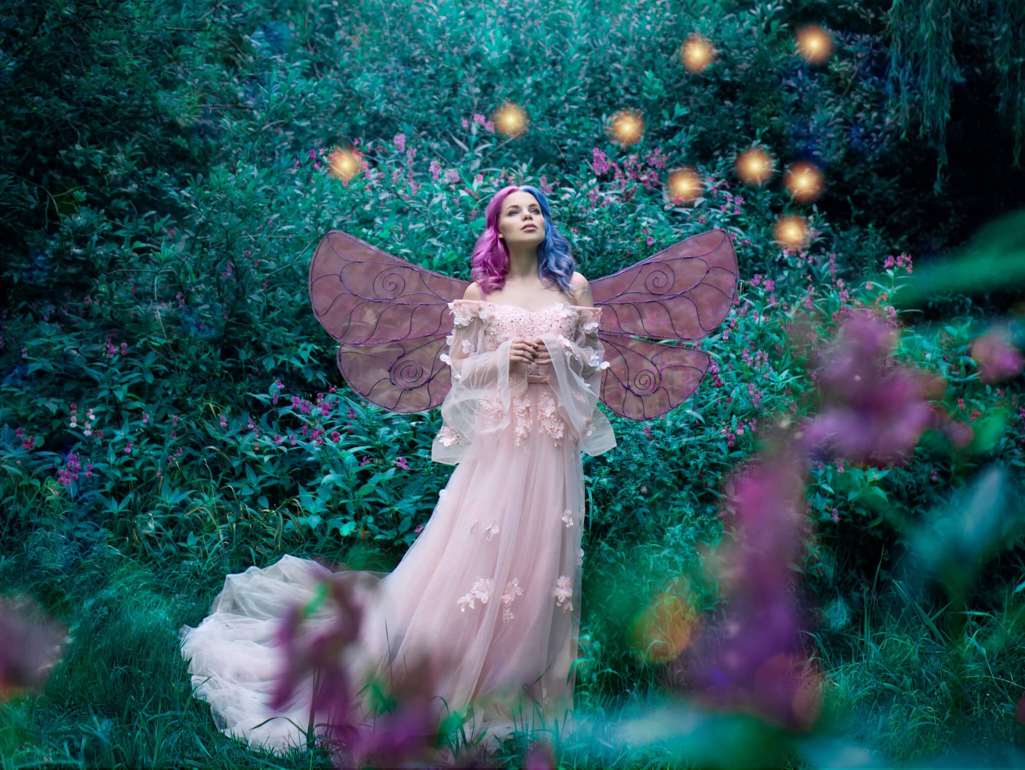 Art photo of a fairy fairy in a pink dress in the forest with fireflies