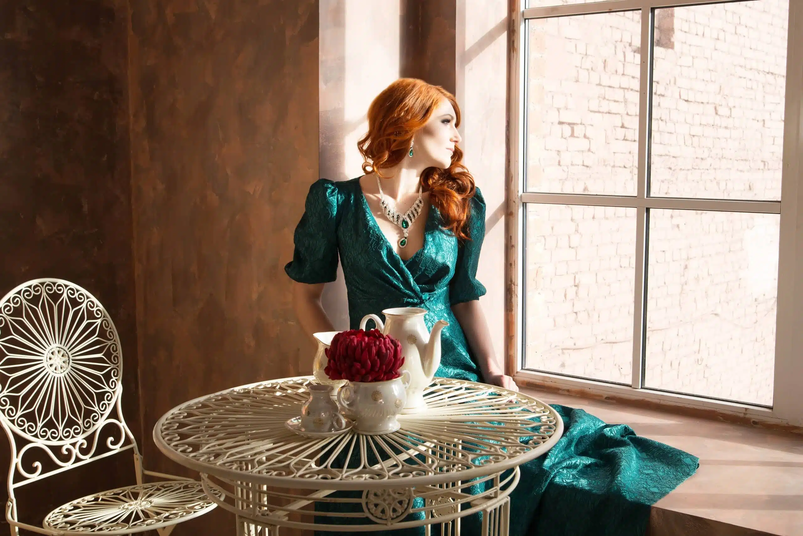 Vintage woman, redhead sitting and looking outside the window.