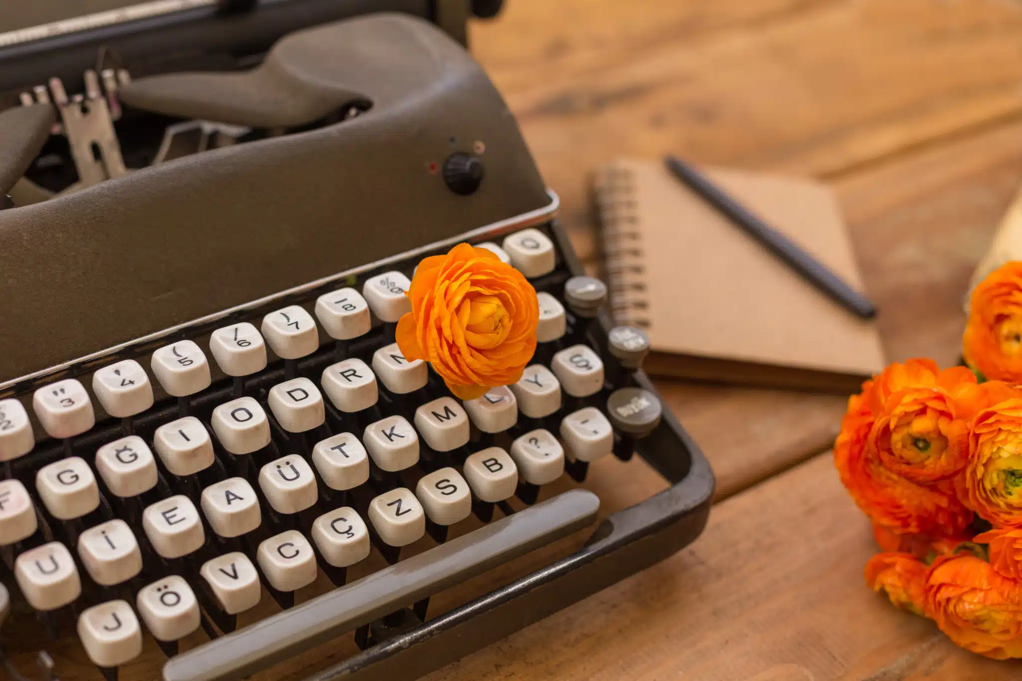 Writing in spring season. Retro typewriter, orange ranunculus an