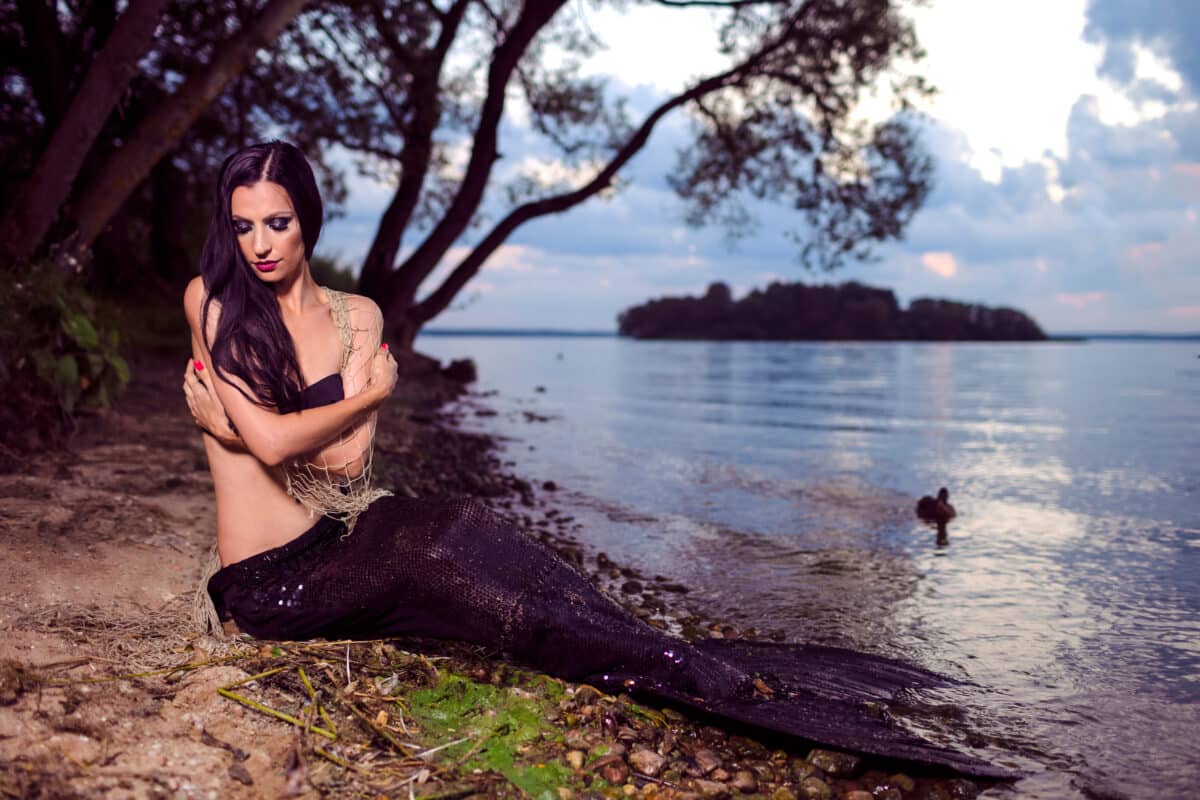 Mermaid Posing With Net Near Sea on Rocks While Wearing Artistic