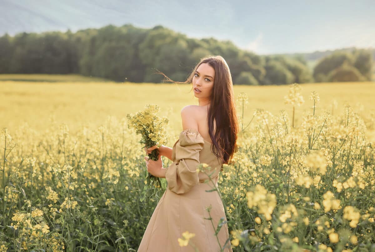 Young woman in the field of flowers with bouquet