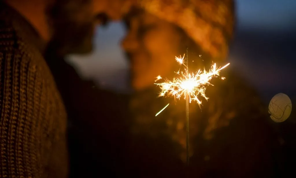 Romantic couple in love celebrate together at event party nightlife with fire sparkler.