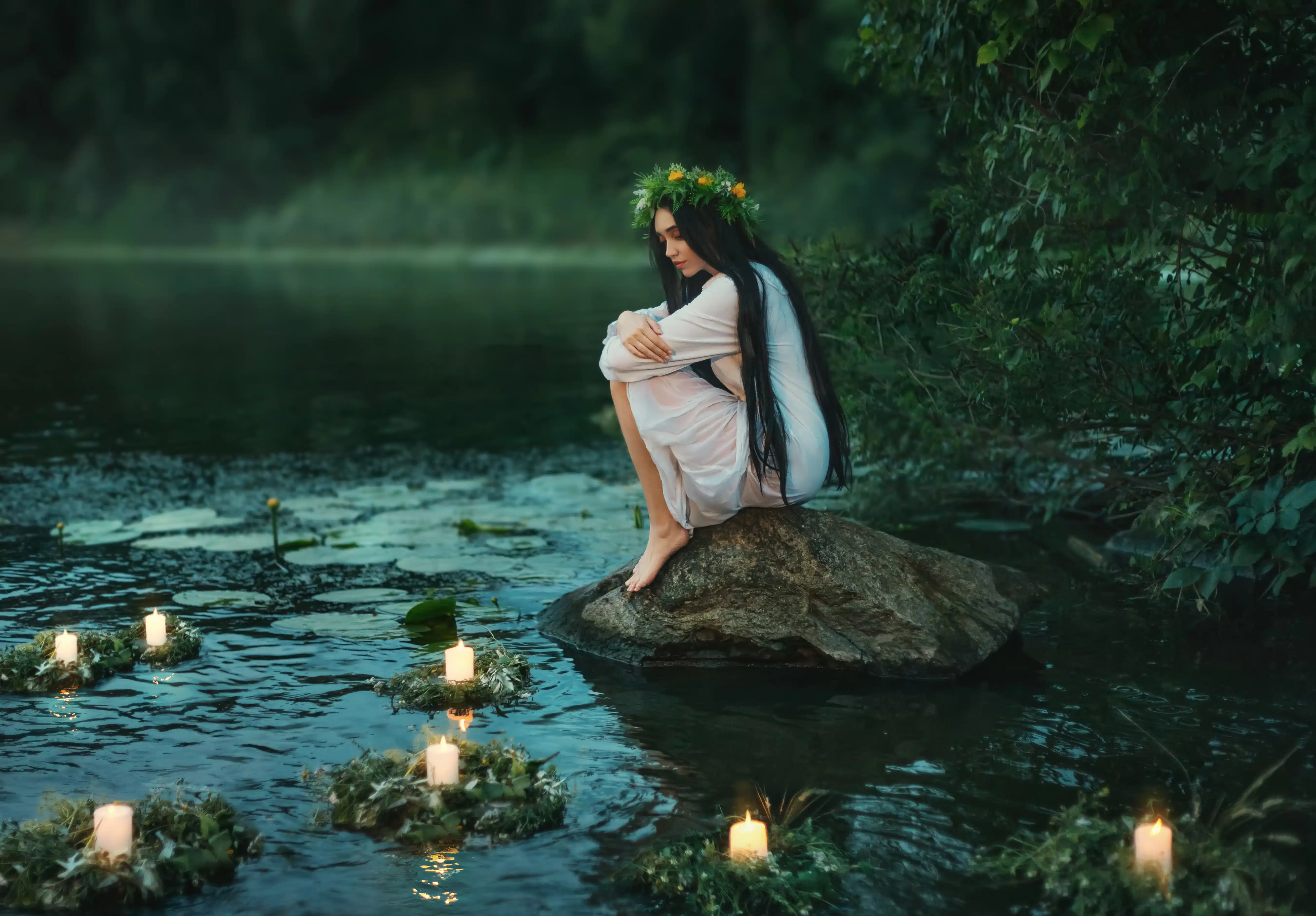 Slavic girl sits on stone on shore lake. 