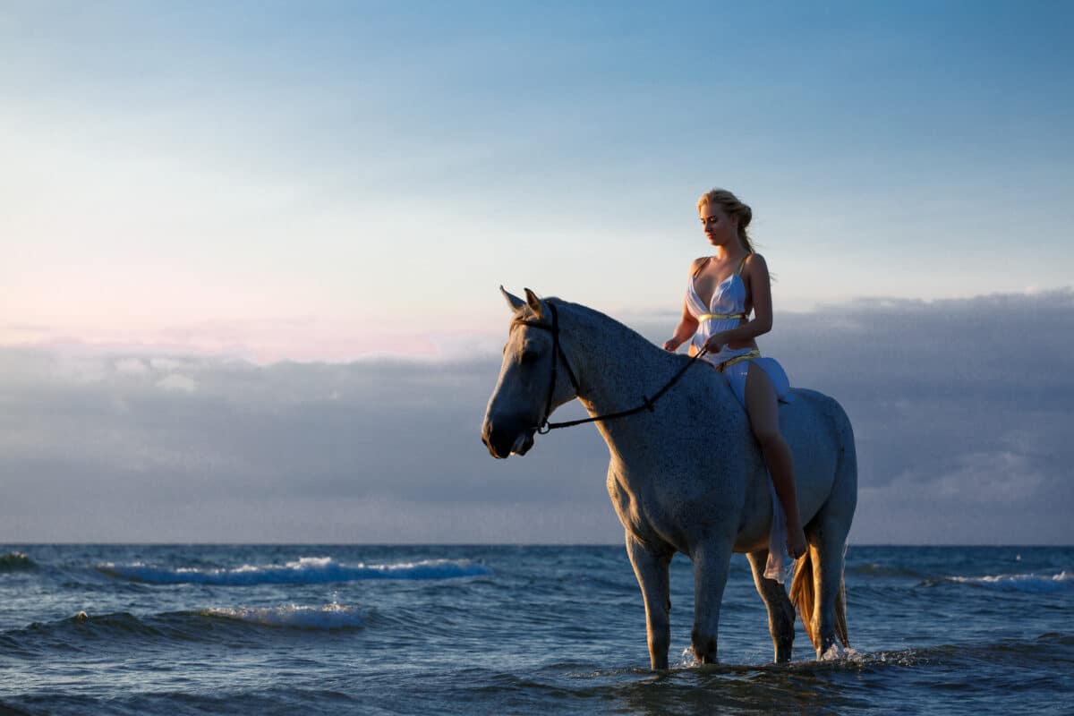 a beautiful young woman on a horse on the beach