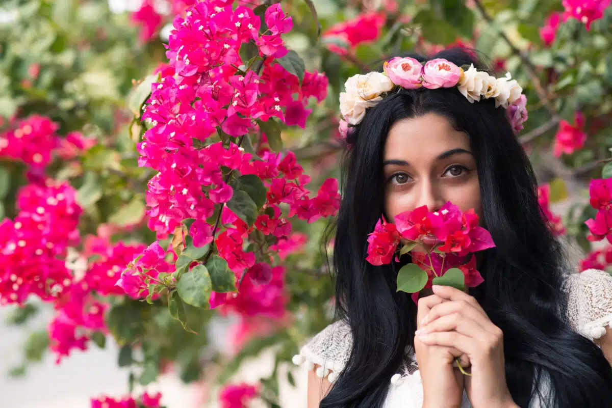 Beautiful young woman holding and smelling pink blossoms in nature