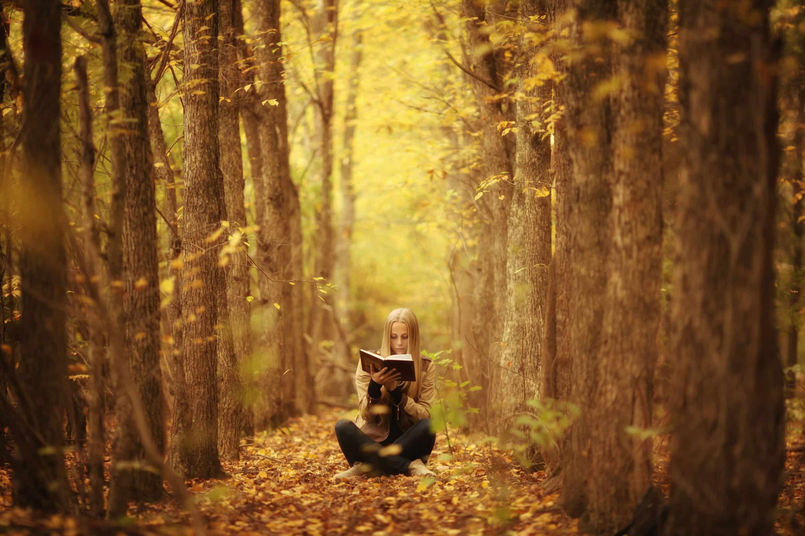 young woman with a book in the autumn forest.