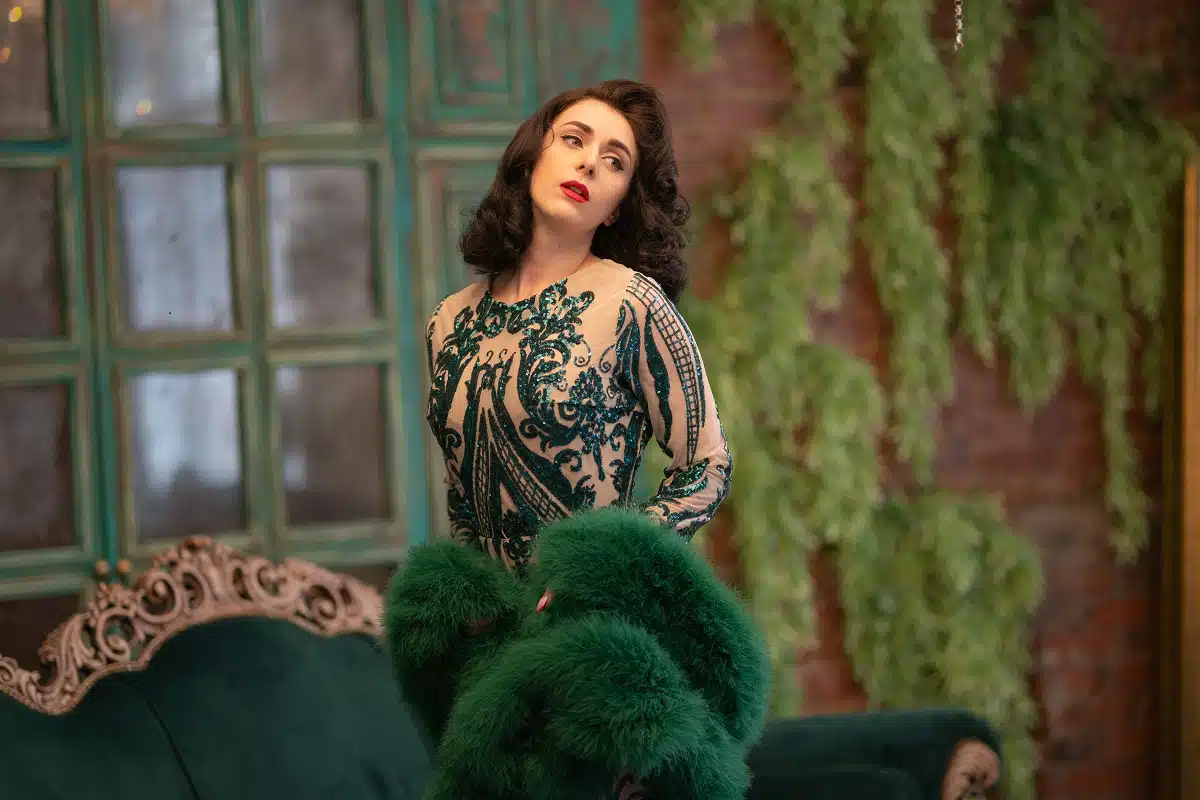an elegant lady in a luxurious long sequined lace dress and a green fluffy boa in her hands in a vintage room