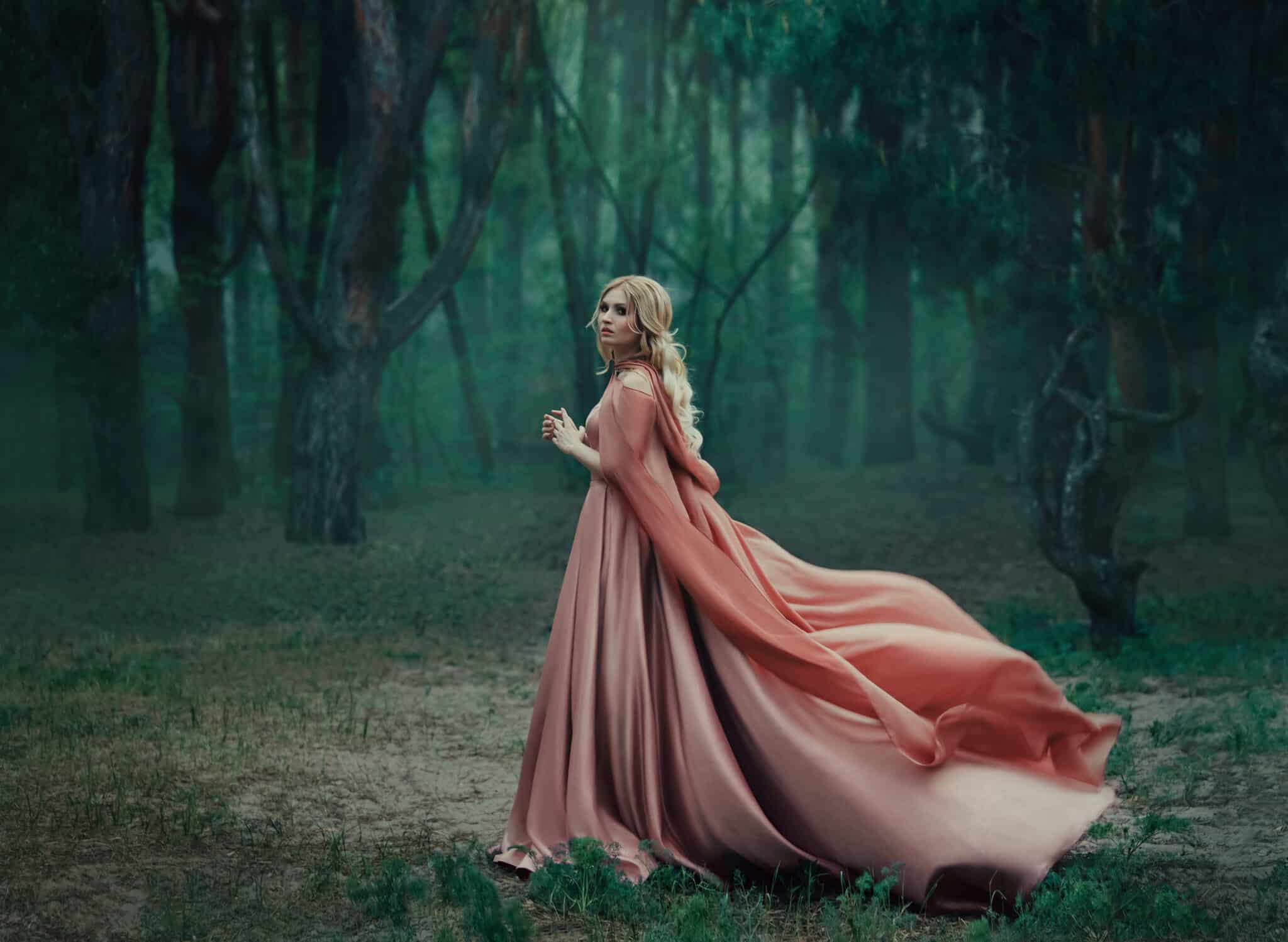 A mysterious blonde girl in a long pink dress with a train and a raincoat that flutters in the wind.