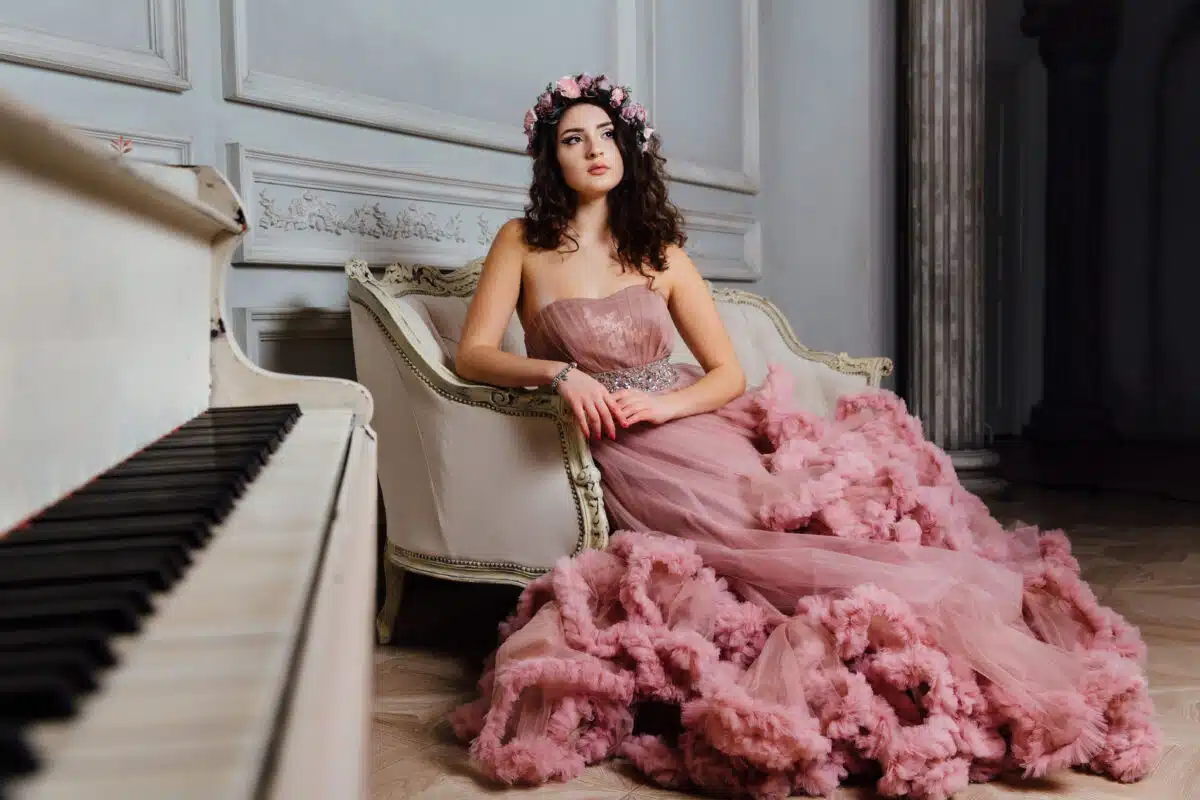 Luxurious lady in an evening cloudy dress sitting on a sofa 