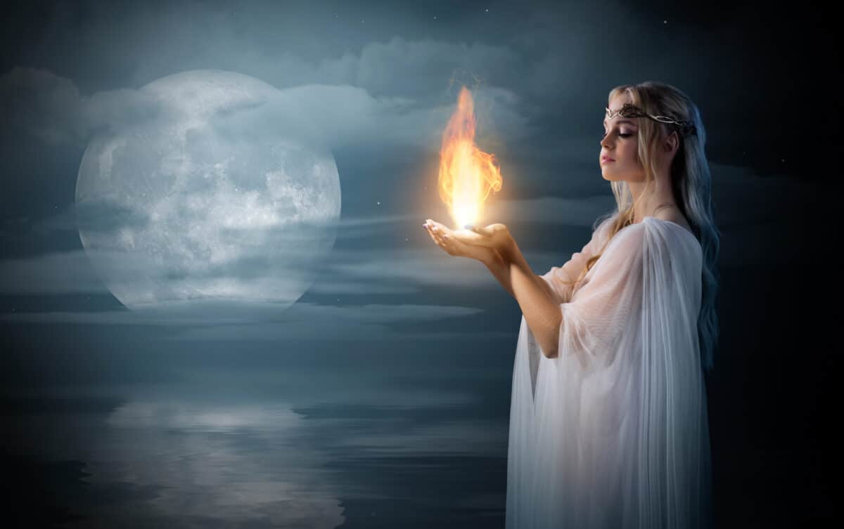 Elven girl holding fire in her palms at sea shore