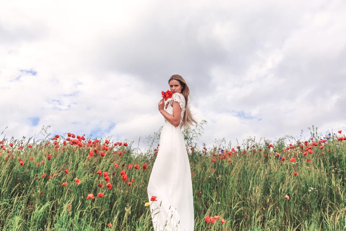 a beautiful lady in white enjoying the poppies in the field
