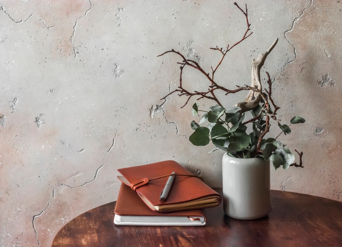 Minimalist style interior design still life - composition of branches and flowers, books, notebooks on a wooden table
