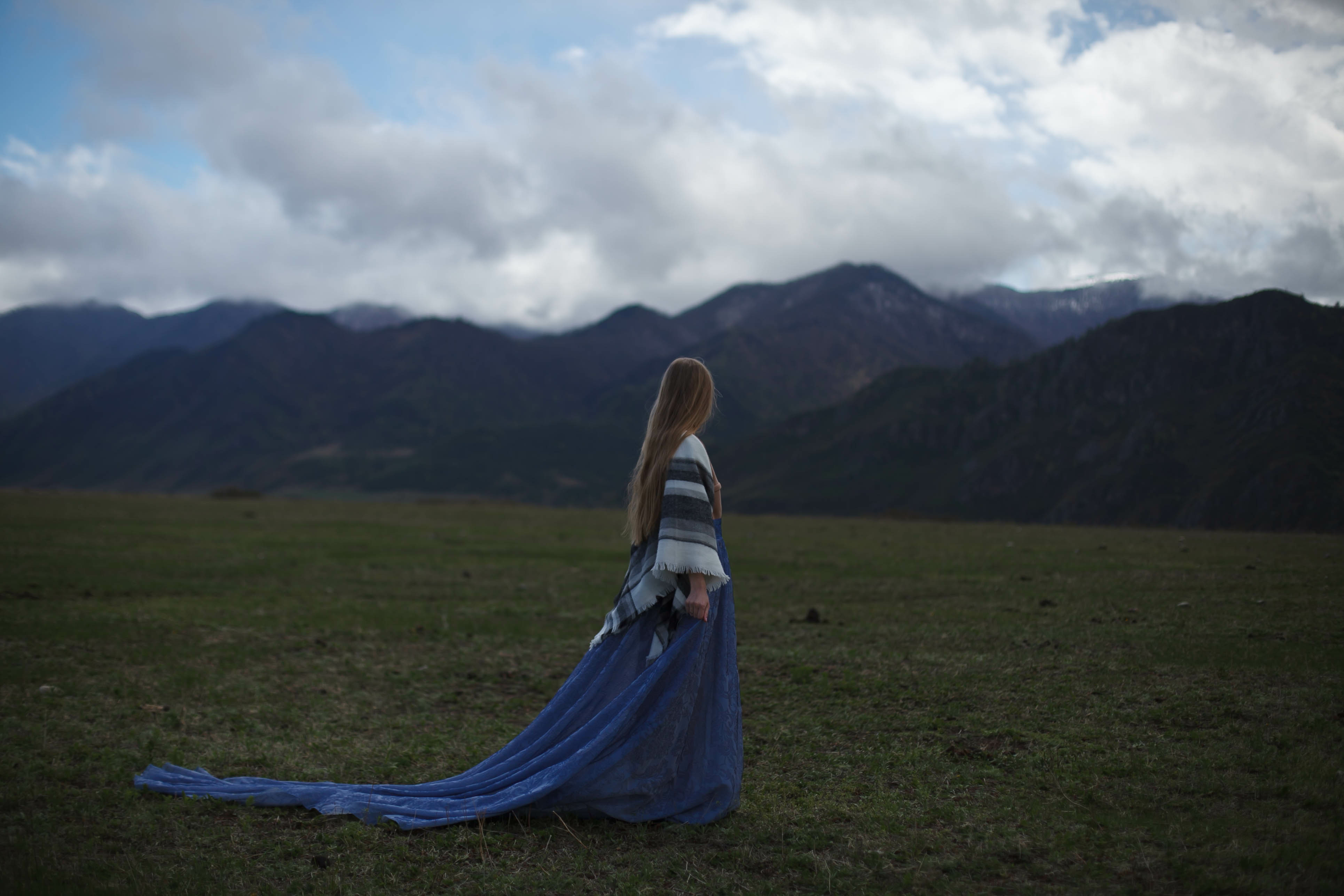 a girl walks in a field on a background of snow-capped mountains