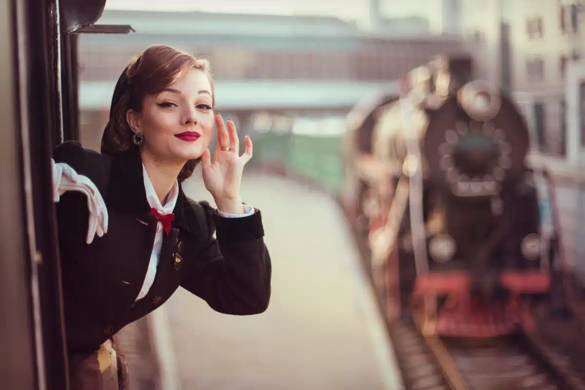 a young beautiful lady and a historical retro locomotive in the background