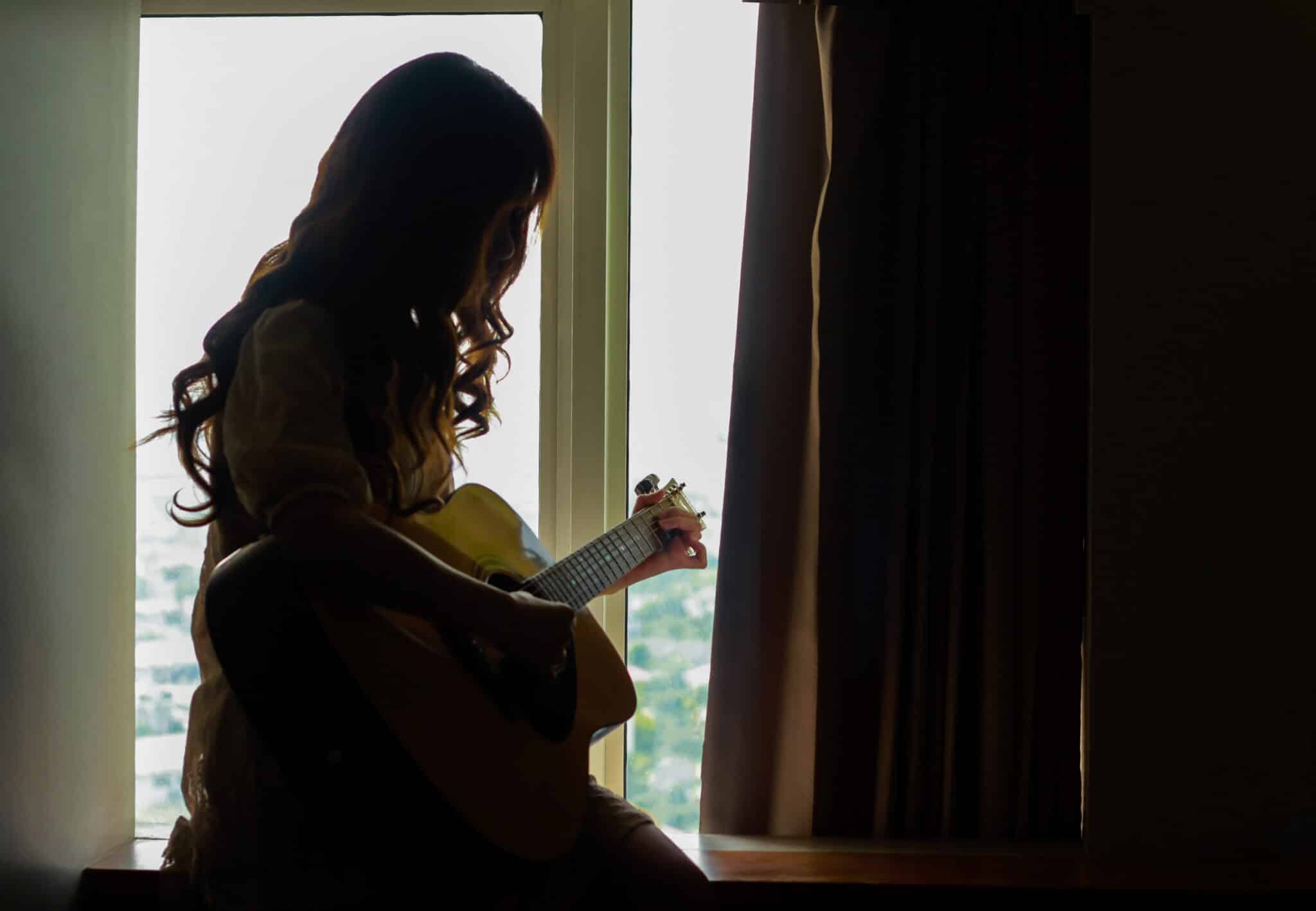 Silhouette of a young woman playing guitar