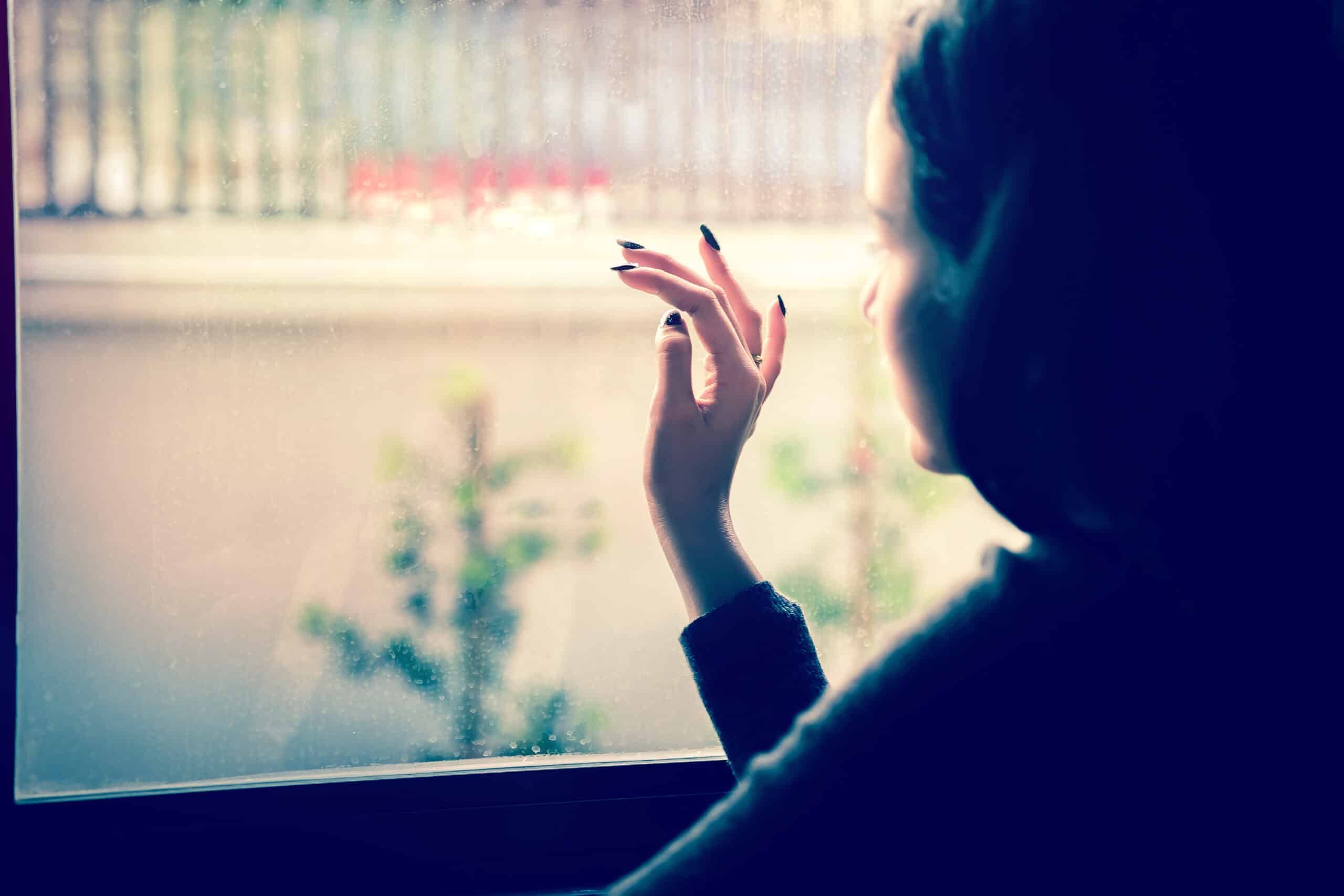 Cute Asian girl sitting by the window with a sad, lonely feeling