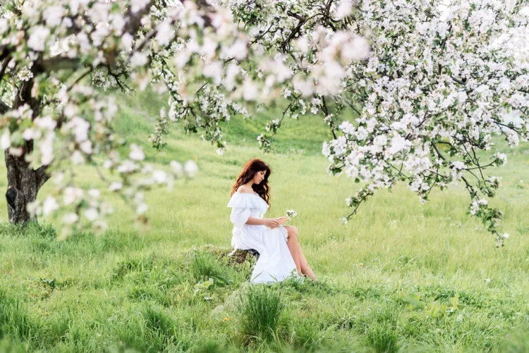 beautiful woman in a white dress reads a book in the spring garden. 