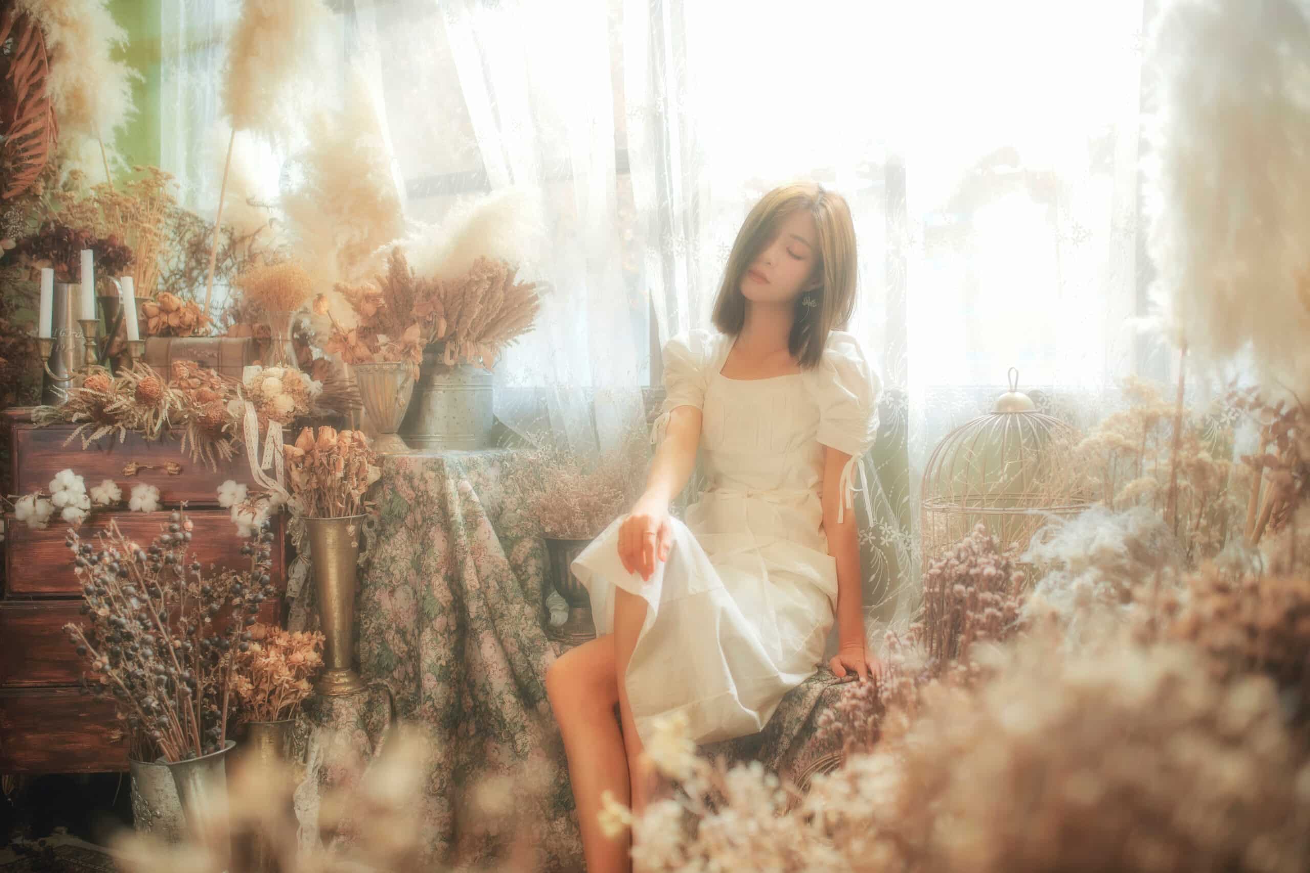 asian young woman in white dress sitting in a flower decorated room