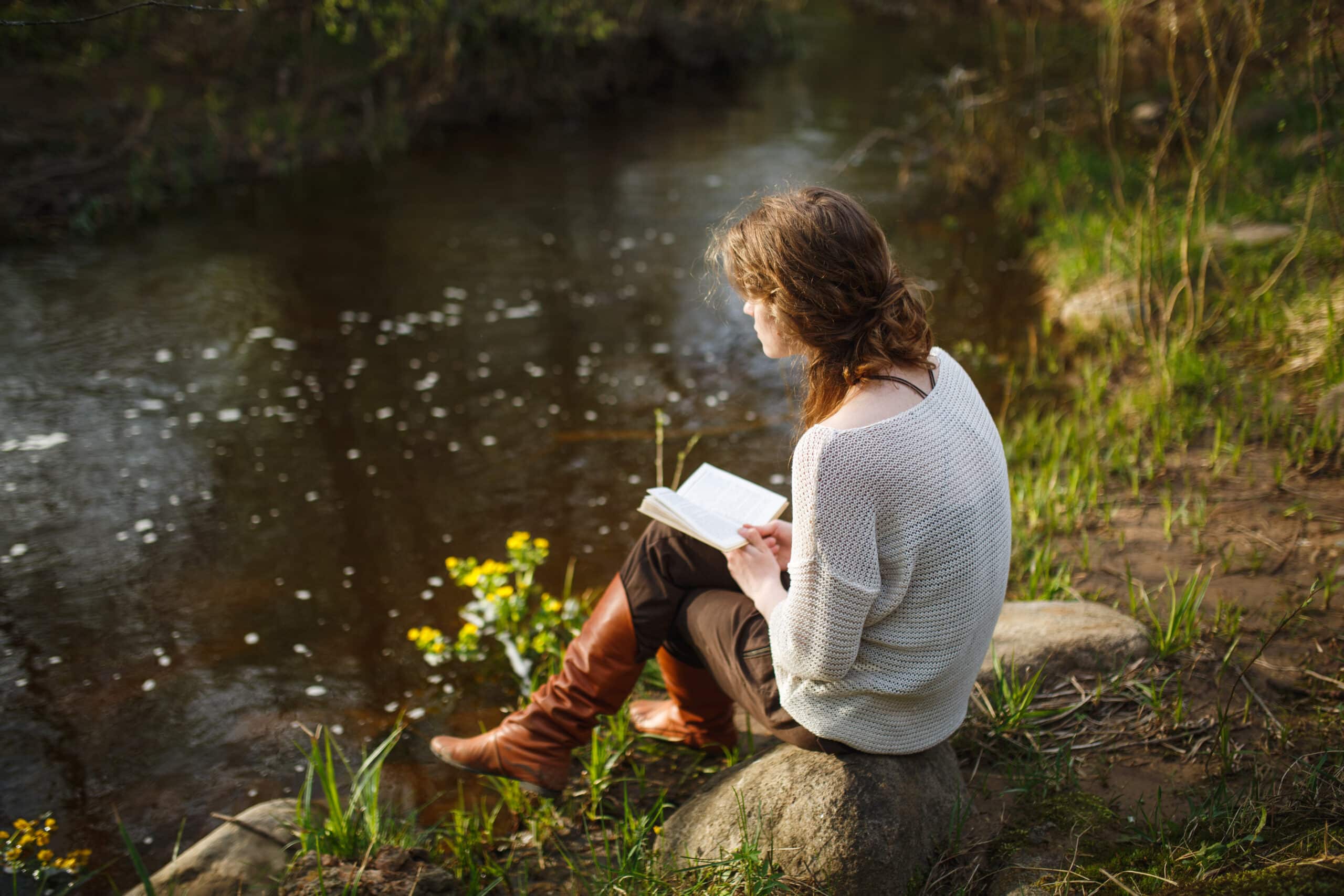 girl reading a book by the river