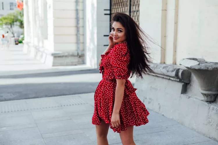 a beautiful brunette woman in a red summer dress on the street