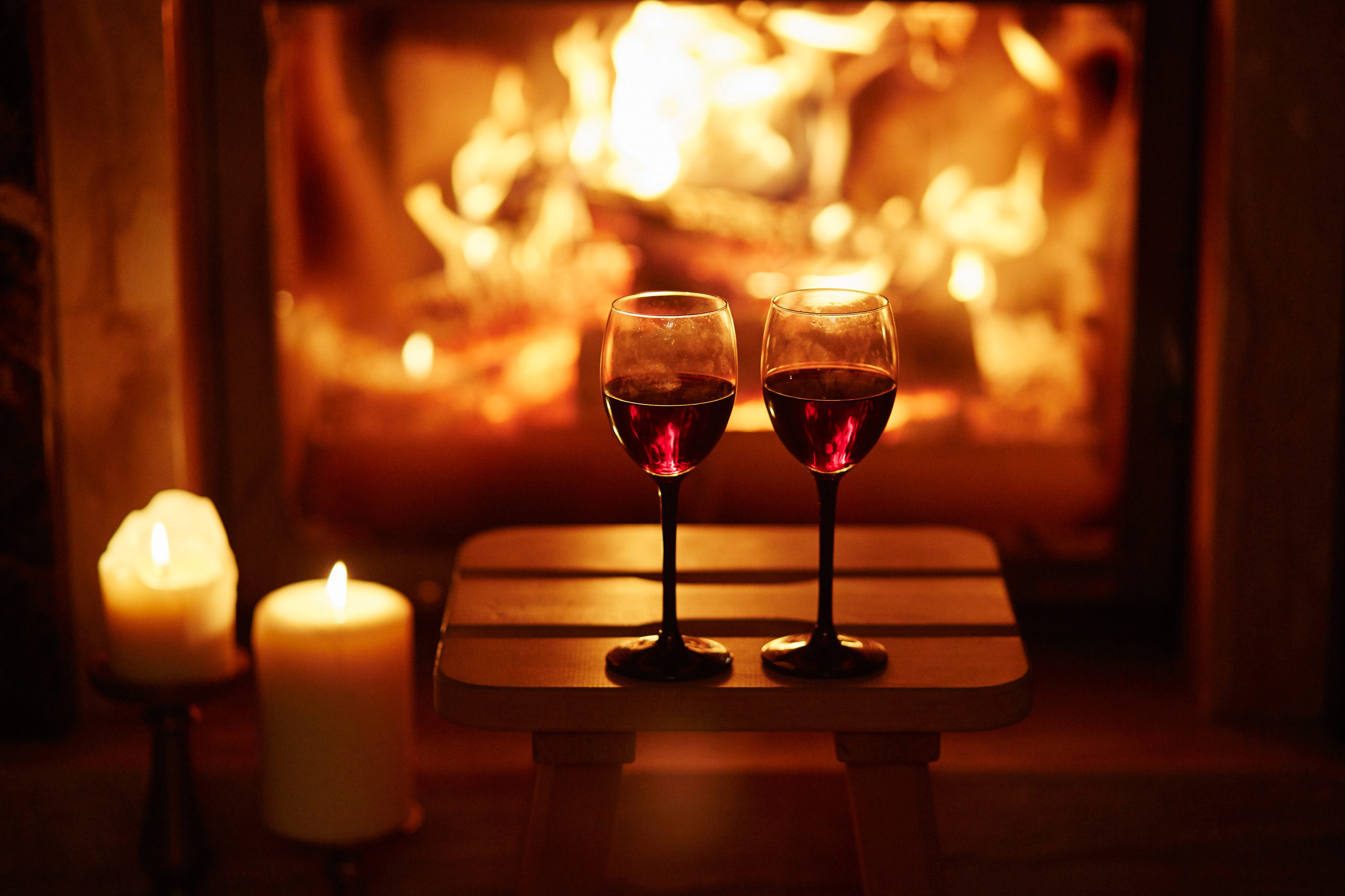 Two glasses of red wine near fireplace