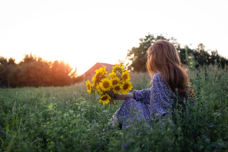 Girl and sunflowers in nature enjoying the sunrise