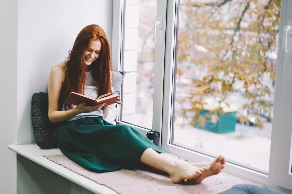 Beautiful girl smiling reading funny poems in book.