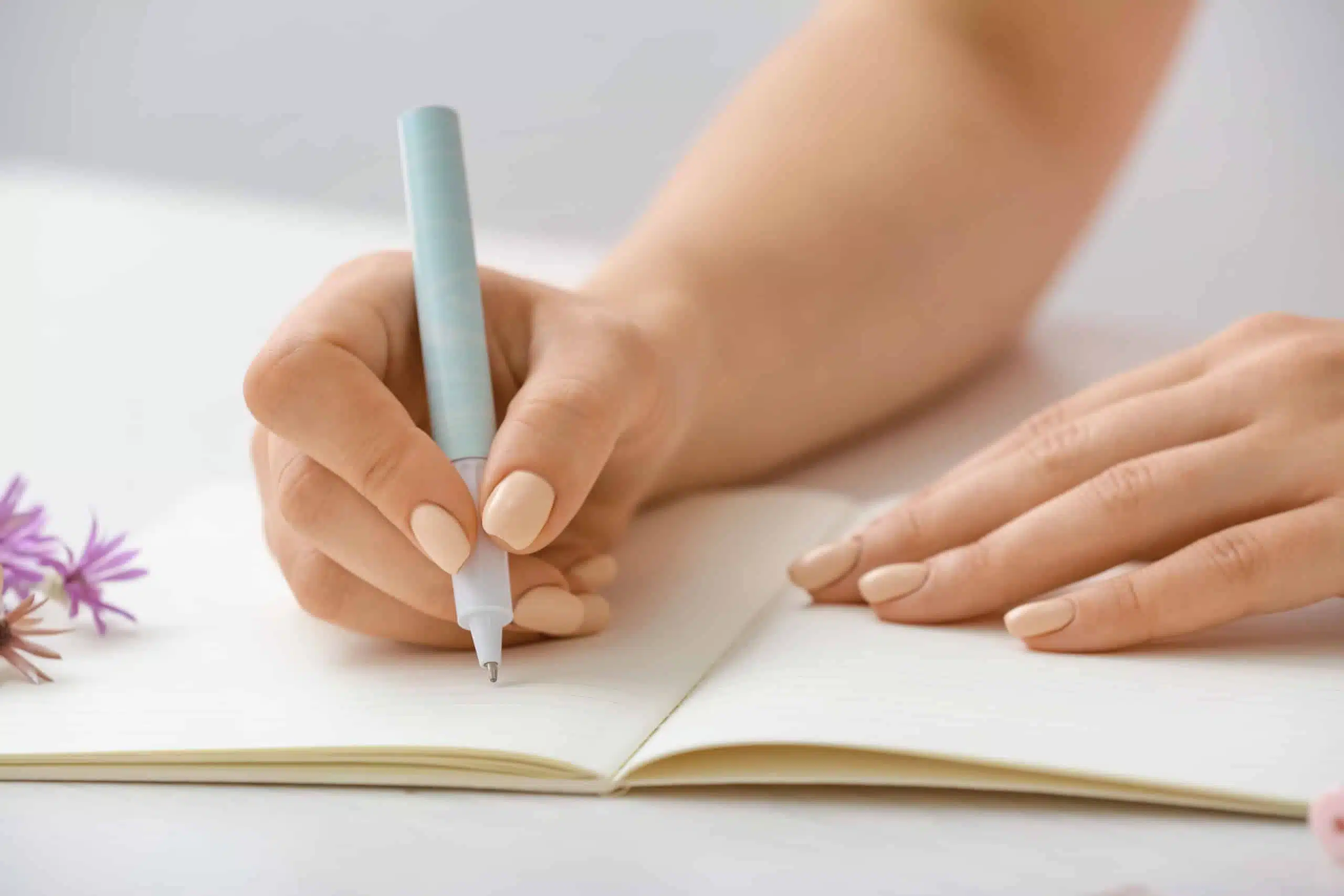 Woman writing in notebook with pen.