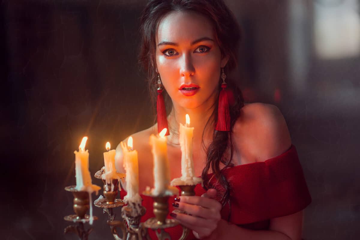 a beautiful lady in red is holding lit candles
