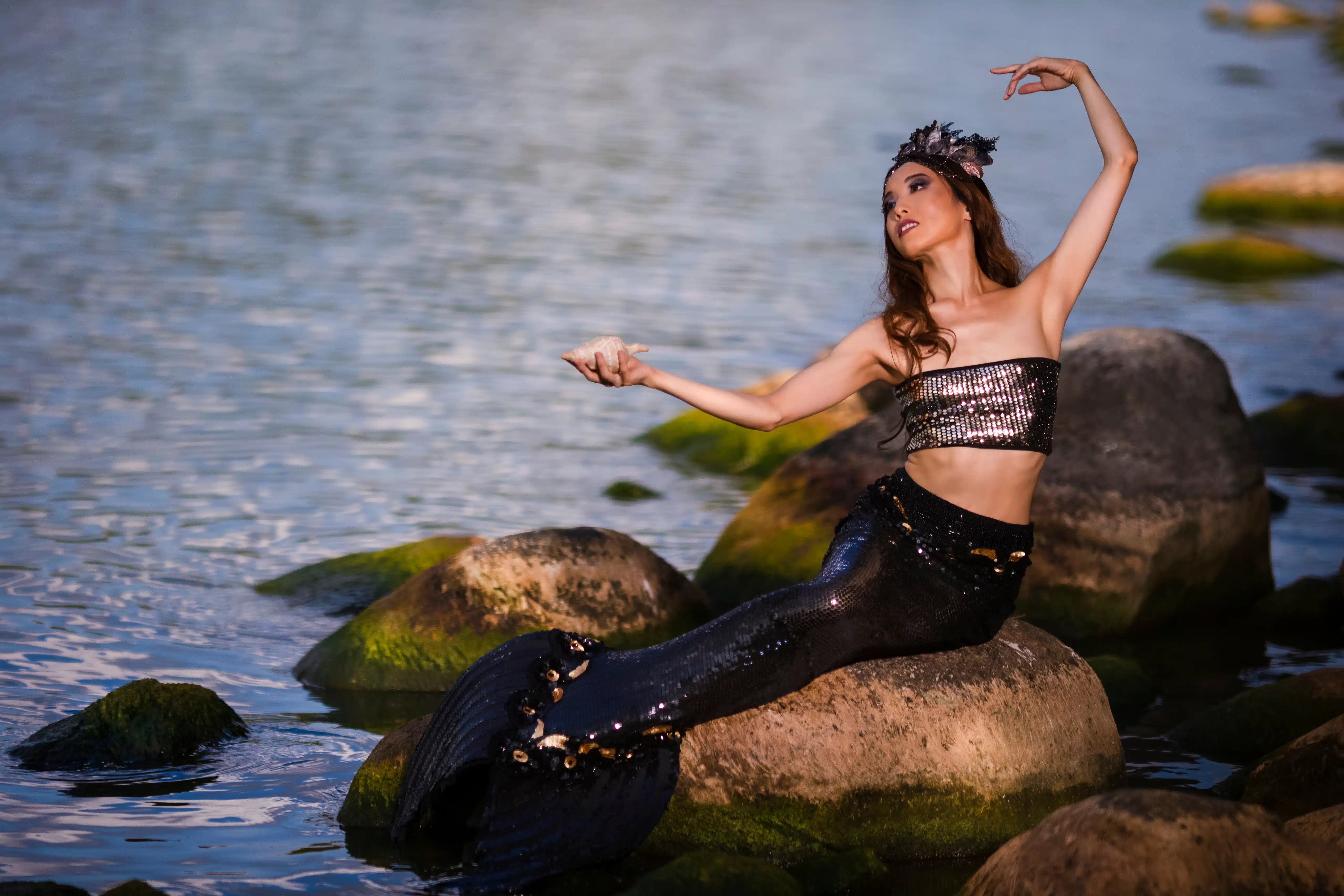 Dancing Asian Mermaid Posing With Seashell At Sea Shore on Rocks