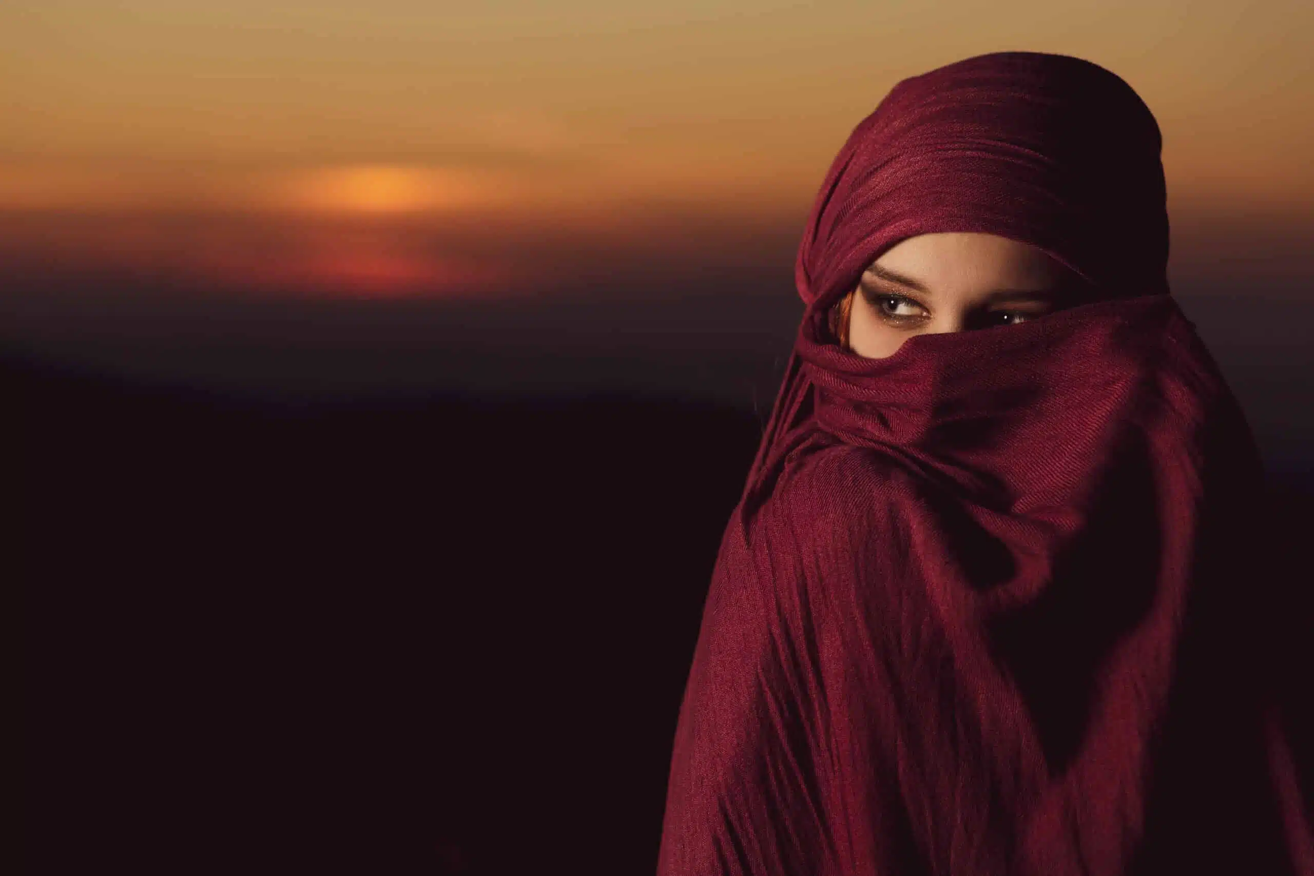 A beautiful young Arabic woman with red scarf at sunset.
