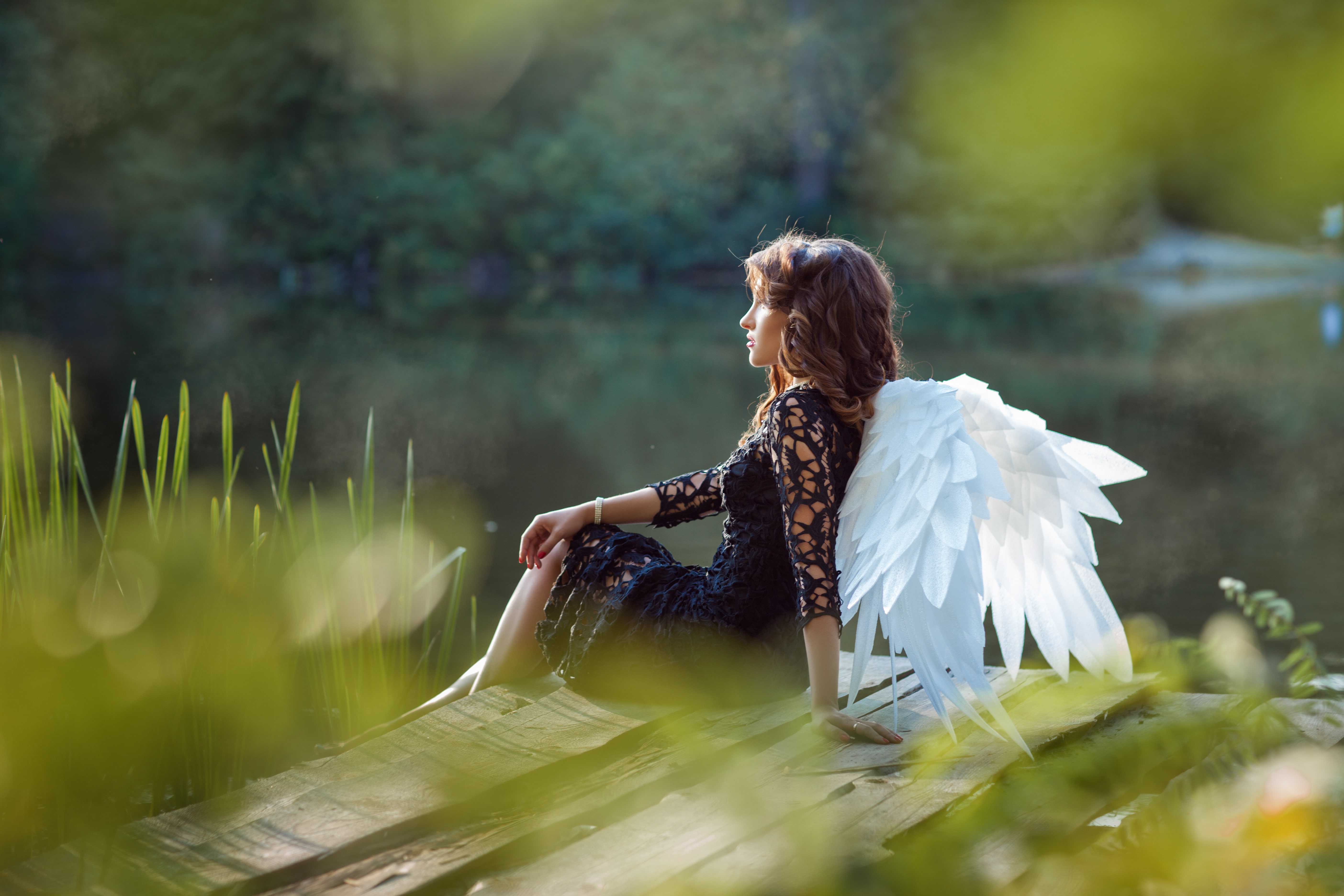 On the pier sits a young woman with angel wings