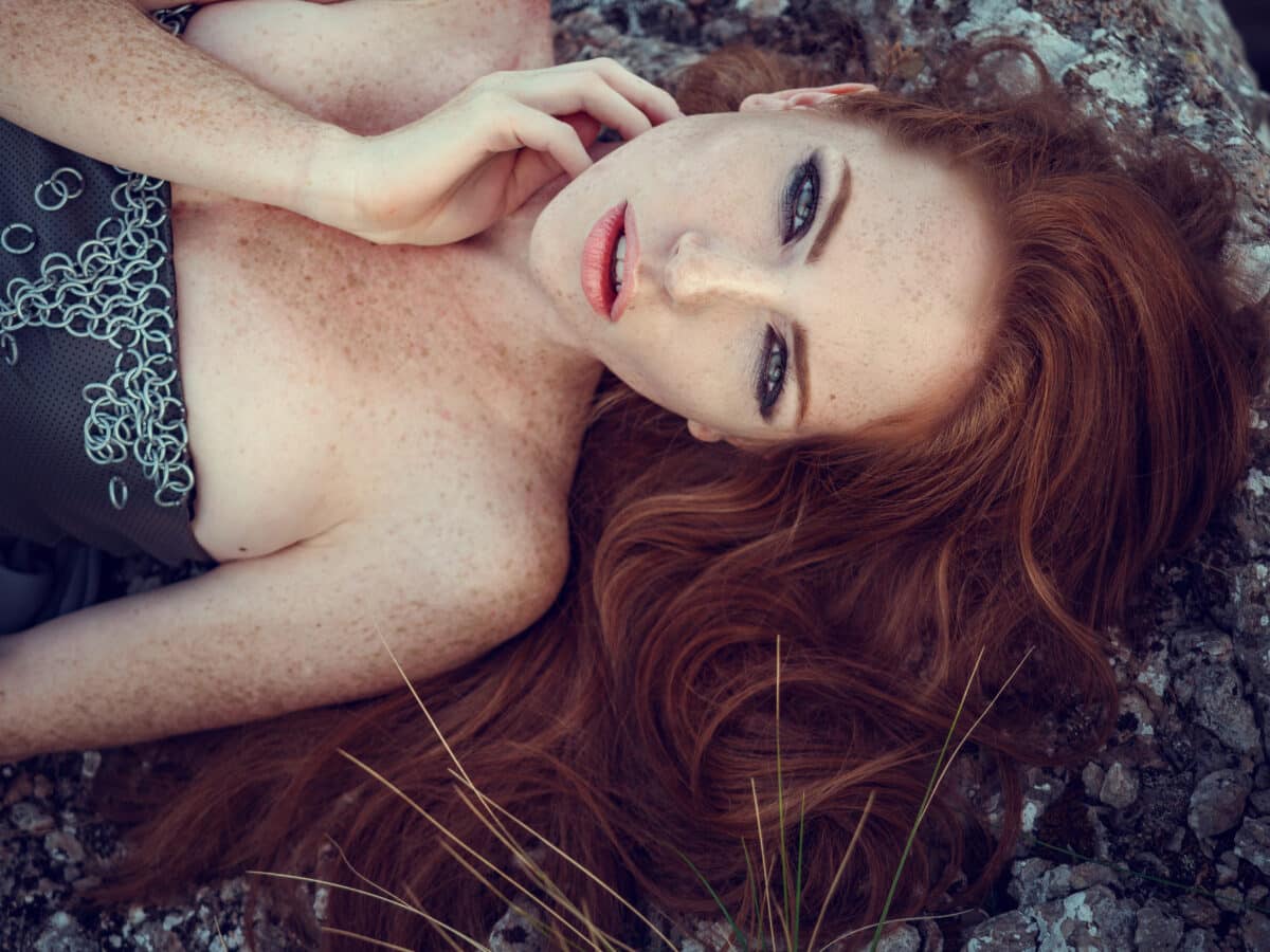 beautiful furious ginger woman in grey dress lying on the ground
