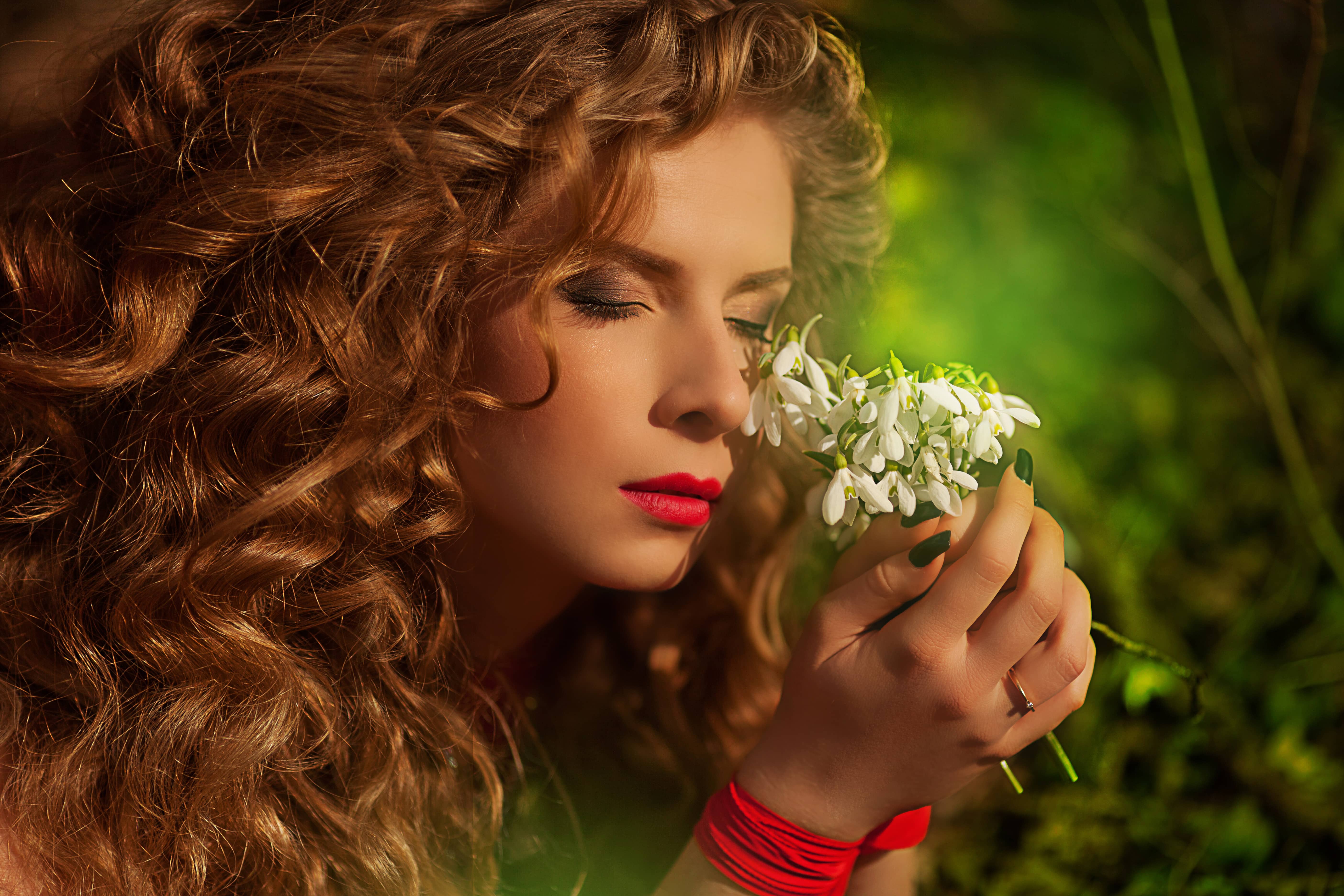 Beautiful woman in long red dress holding white flowers