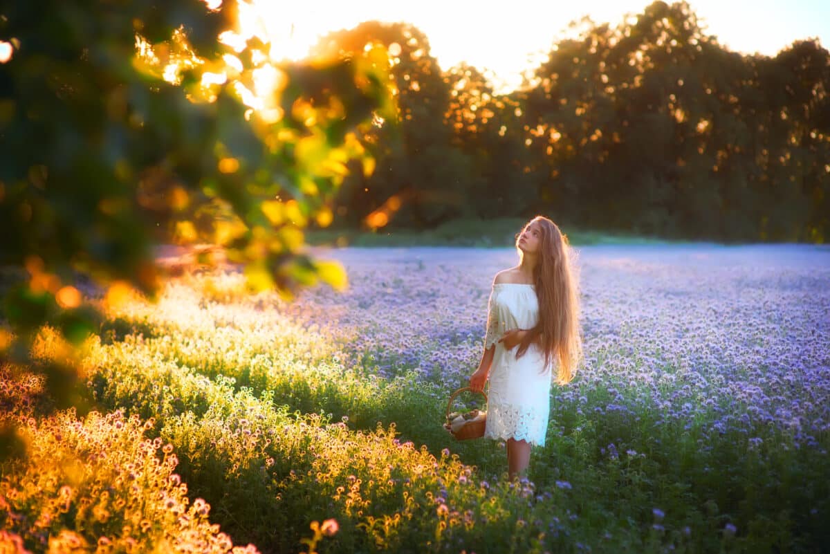 A girl with beautiful long hair walks through a flower field