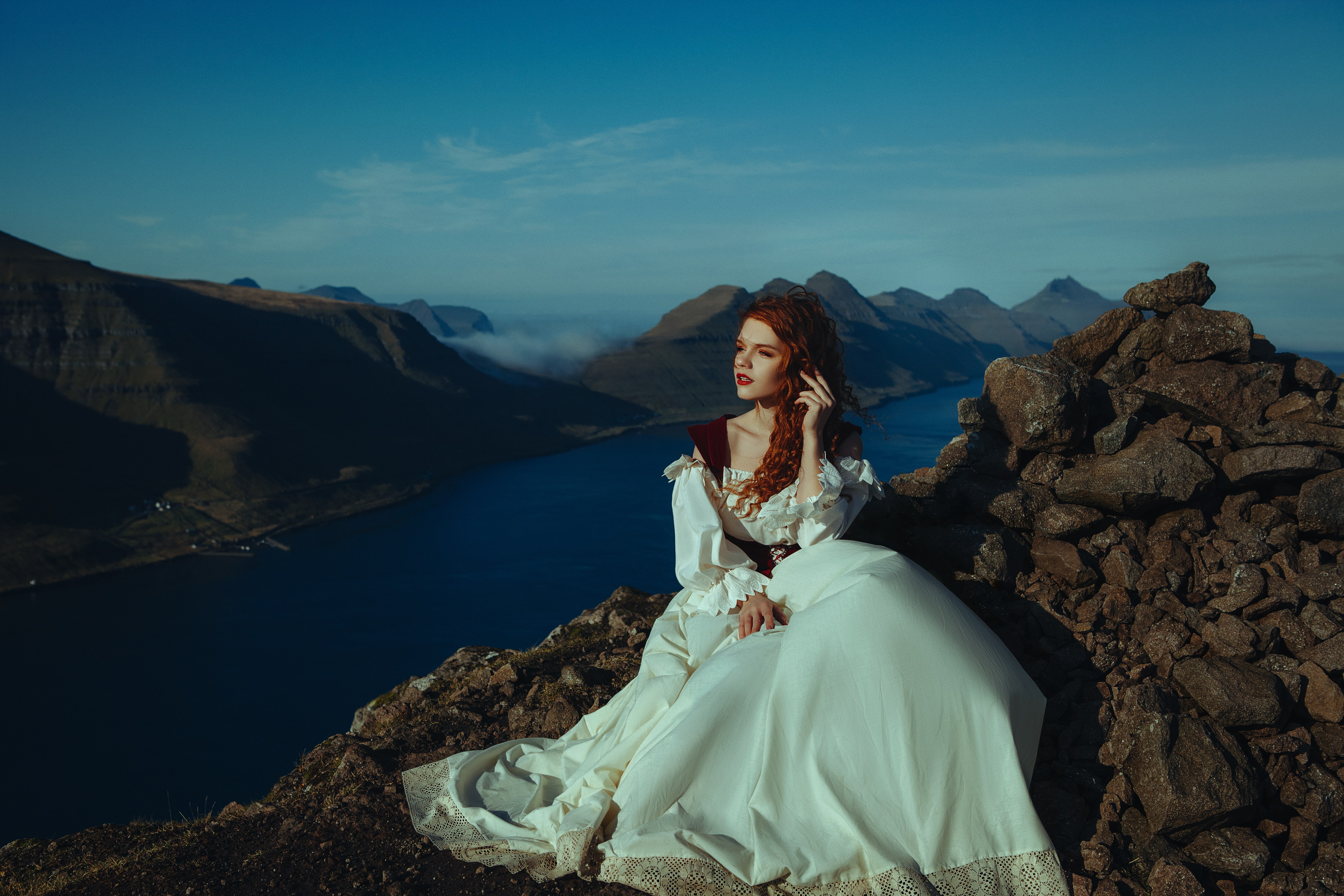 Beautiful red-haired lady on the top of the mountain over the ocean