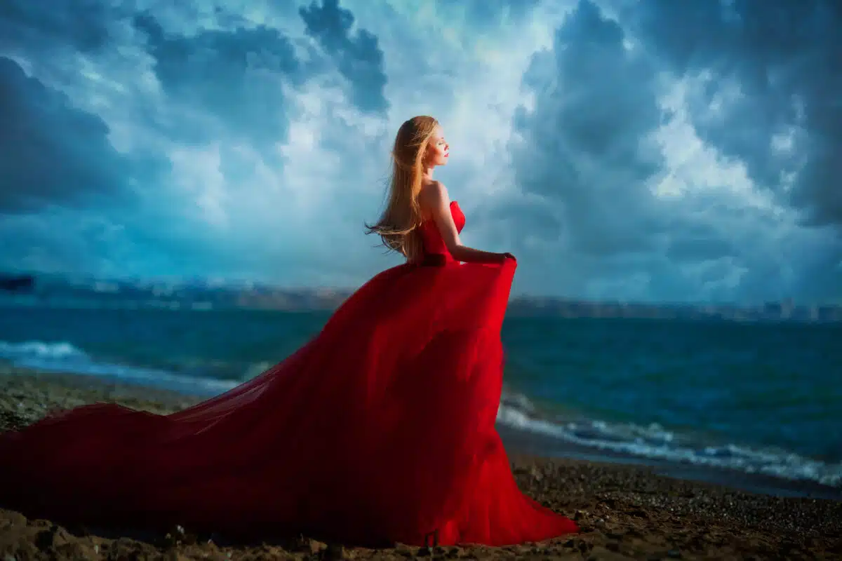 Beautiful girl by the sea. A woman in a red dress on the beach.