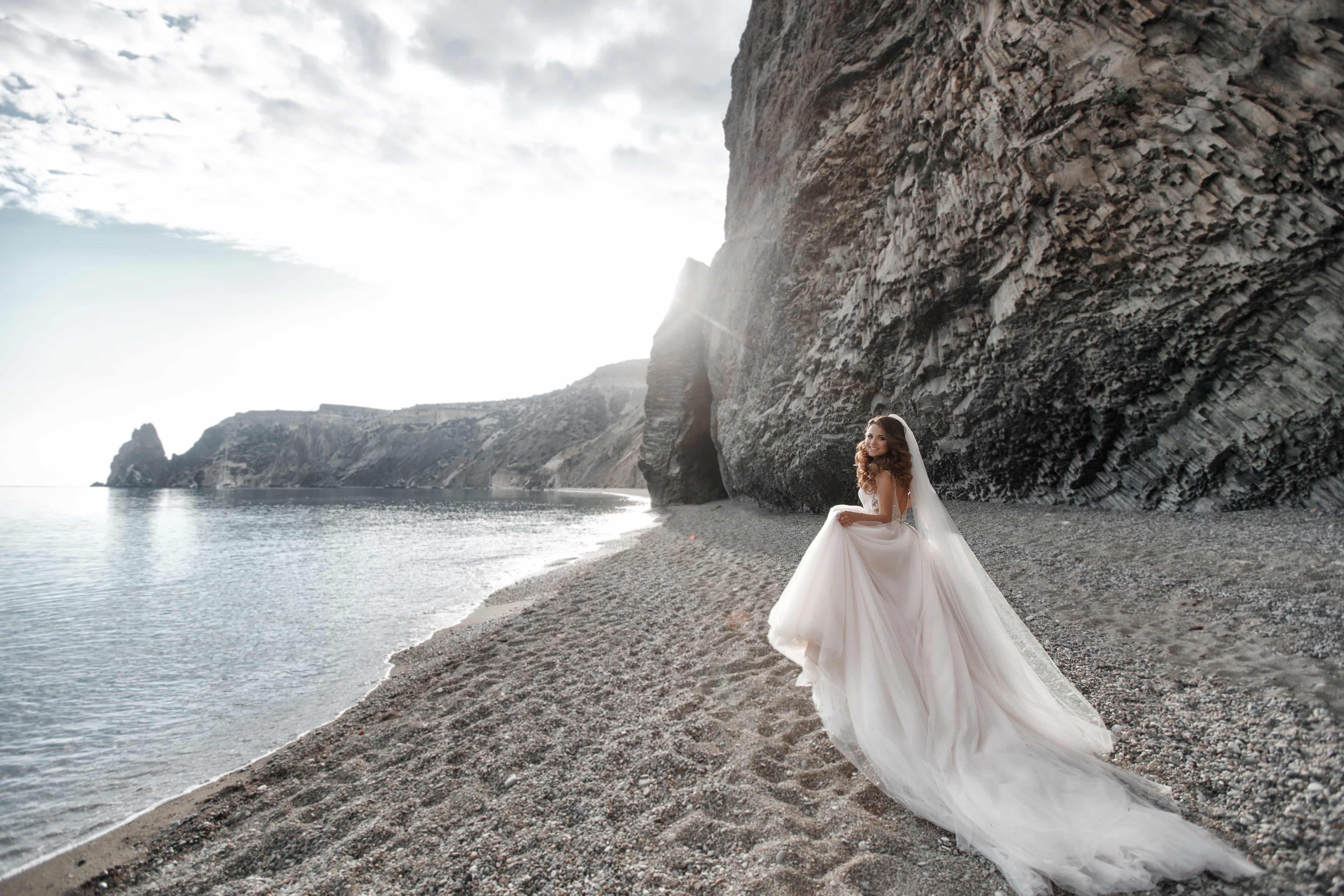 bride by sea with gentle waves and mountains
