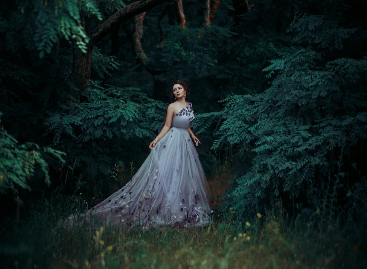 Beautiful girl in a gorgeous long dress, walk among the trees